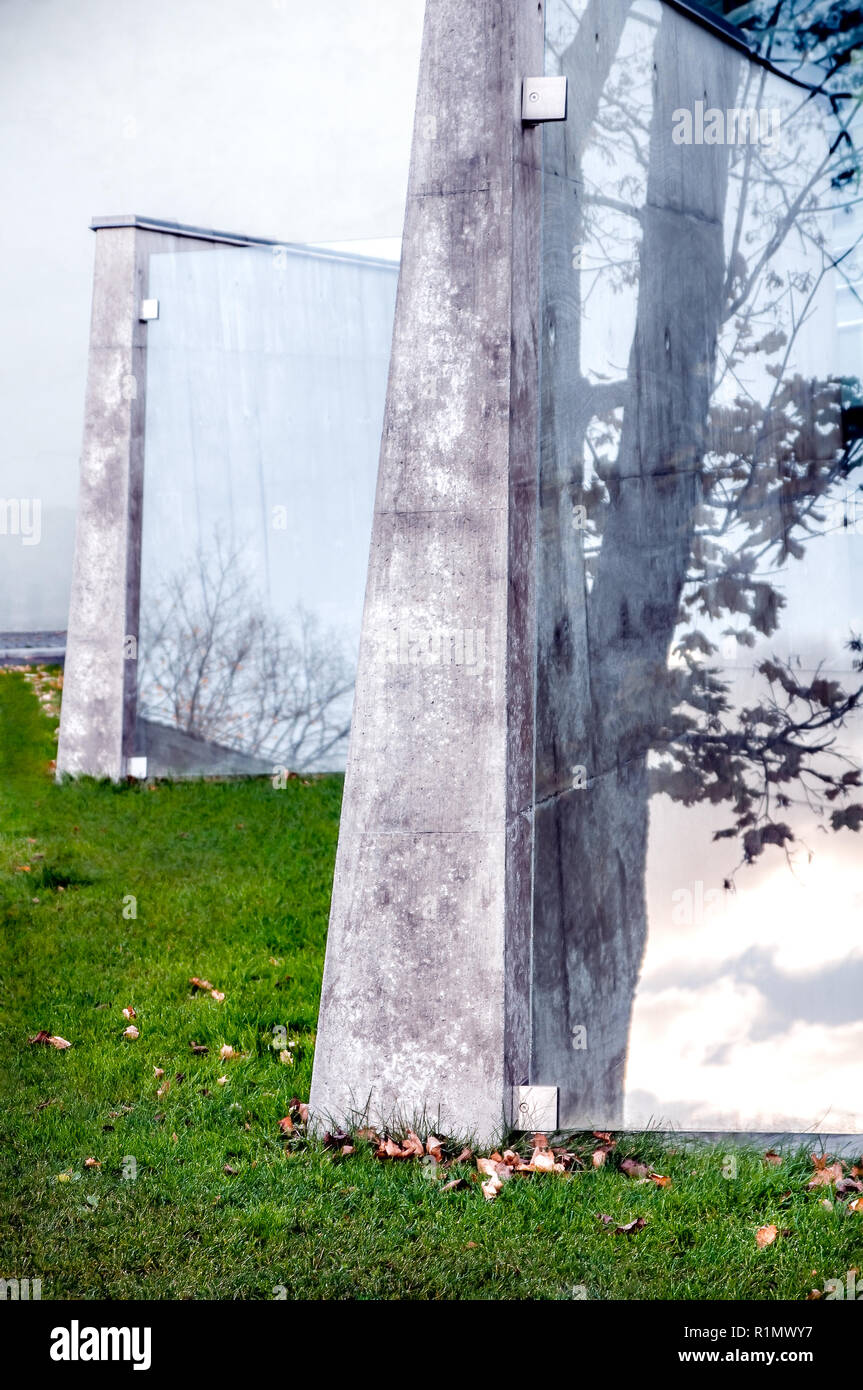 Moderne öffentliche architektonische Attraktion von Zement und Windows mit reflektiertem Baum Silhouette und Wolken im Herbst Landschaft - Kontraste der coolen Urban Design Gebäude und Herbst Natur im Sonnenuntergang Stockfoto