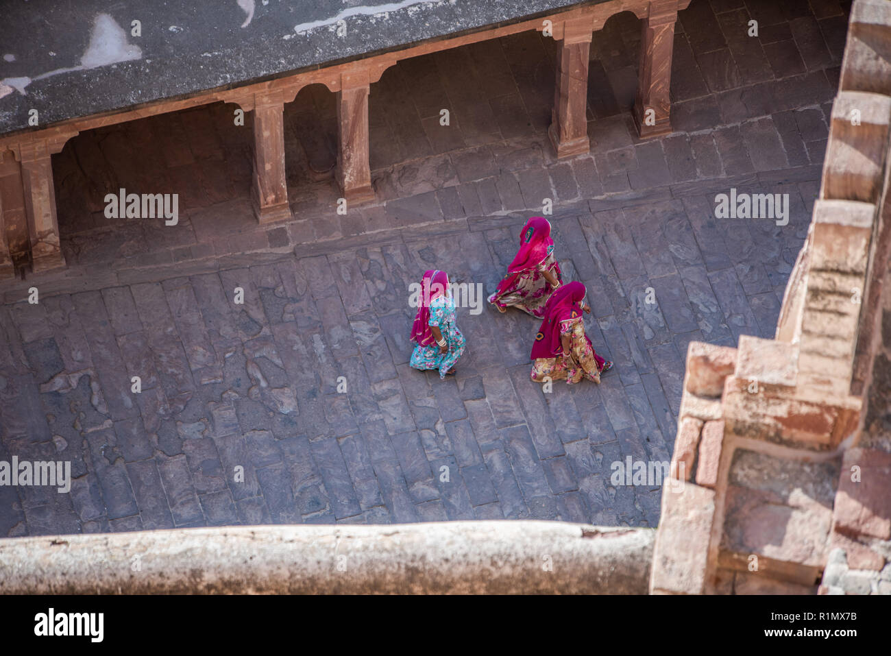 Drei Frauen in farbenfrohen traditionellen Rajasthani Kleider gehen über einen Innenhof in Jodhpur, Indien. Stockfoto