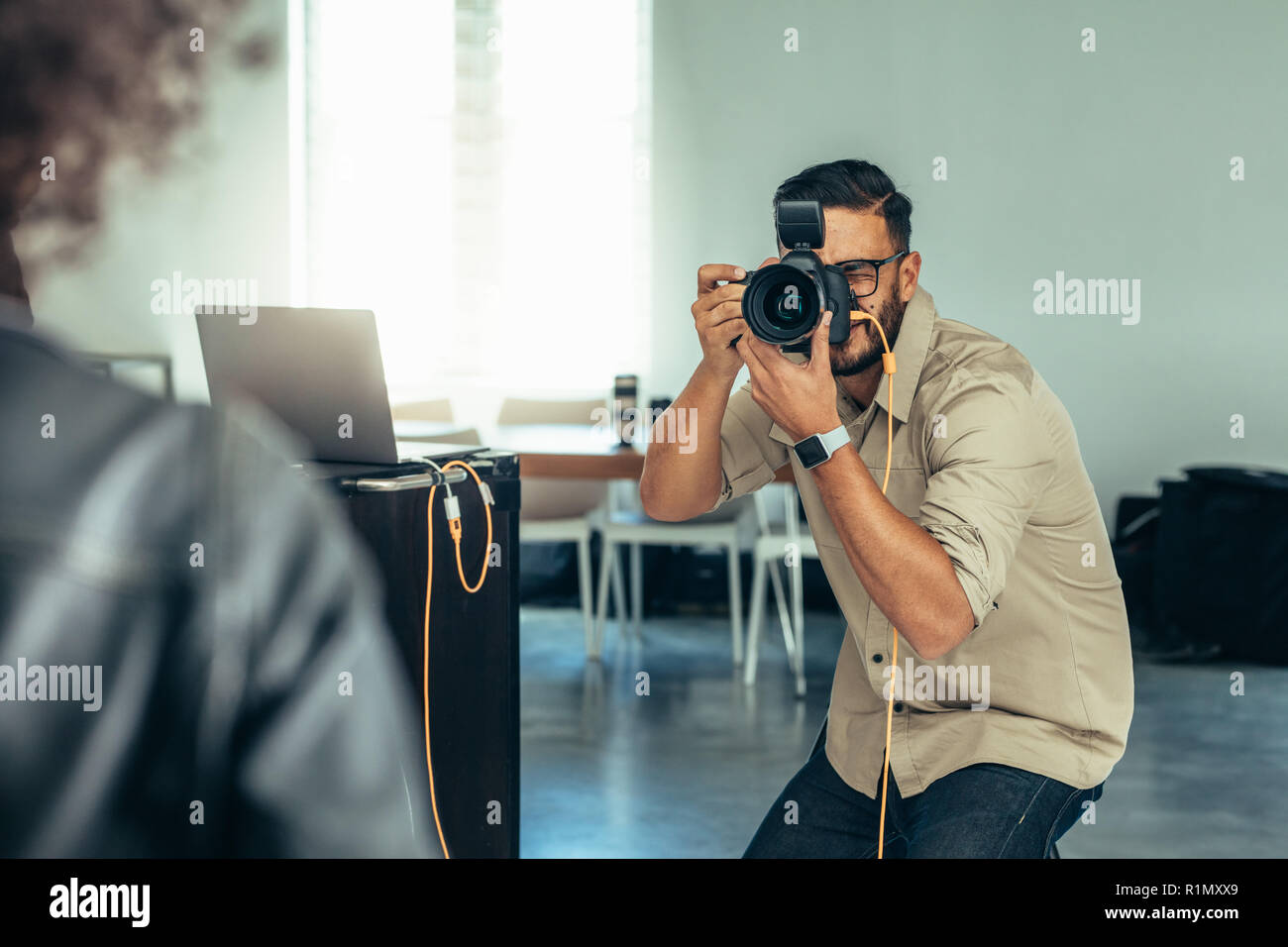 Fotograf in ein Fotoshooting mit einer digitalen Kamera an einen Laptop angeschlossen. Fotograf in Position ein Foto zu machen. Stockfoto