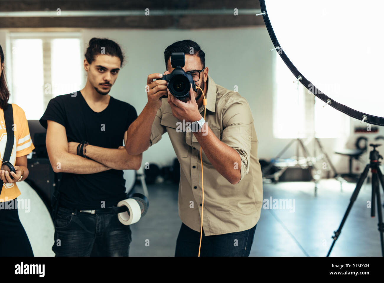 Fotograf mit seinem Team ein Fotoshooting im Studio. Fotograf Fotografieren mit Blitzlicht auf. Stockfoto