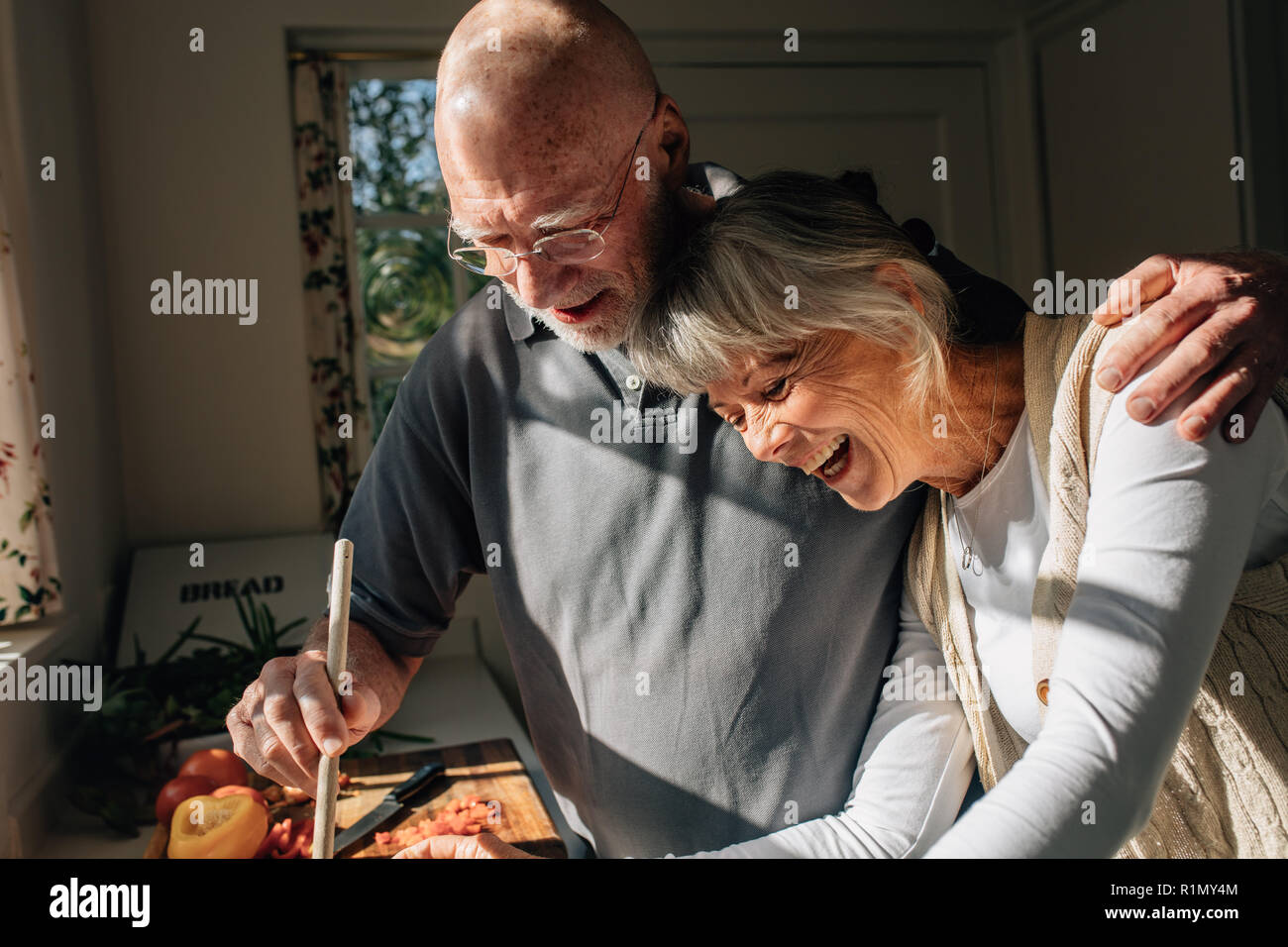 Ältere Menschen kochen seine Frau bestand in seinem Arm stehen in der Küche. Senior Paar gute Zeit Kochen gemeinsam zu Hause. Stockfoto