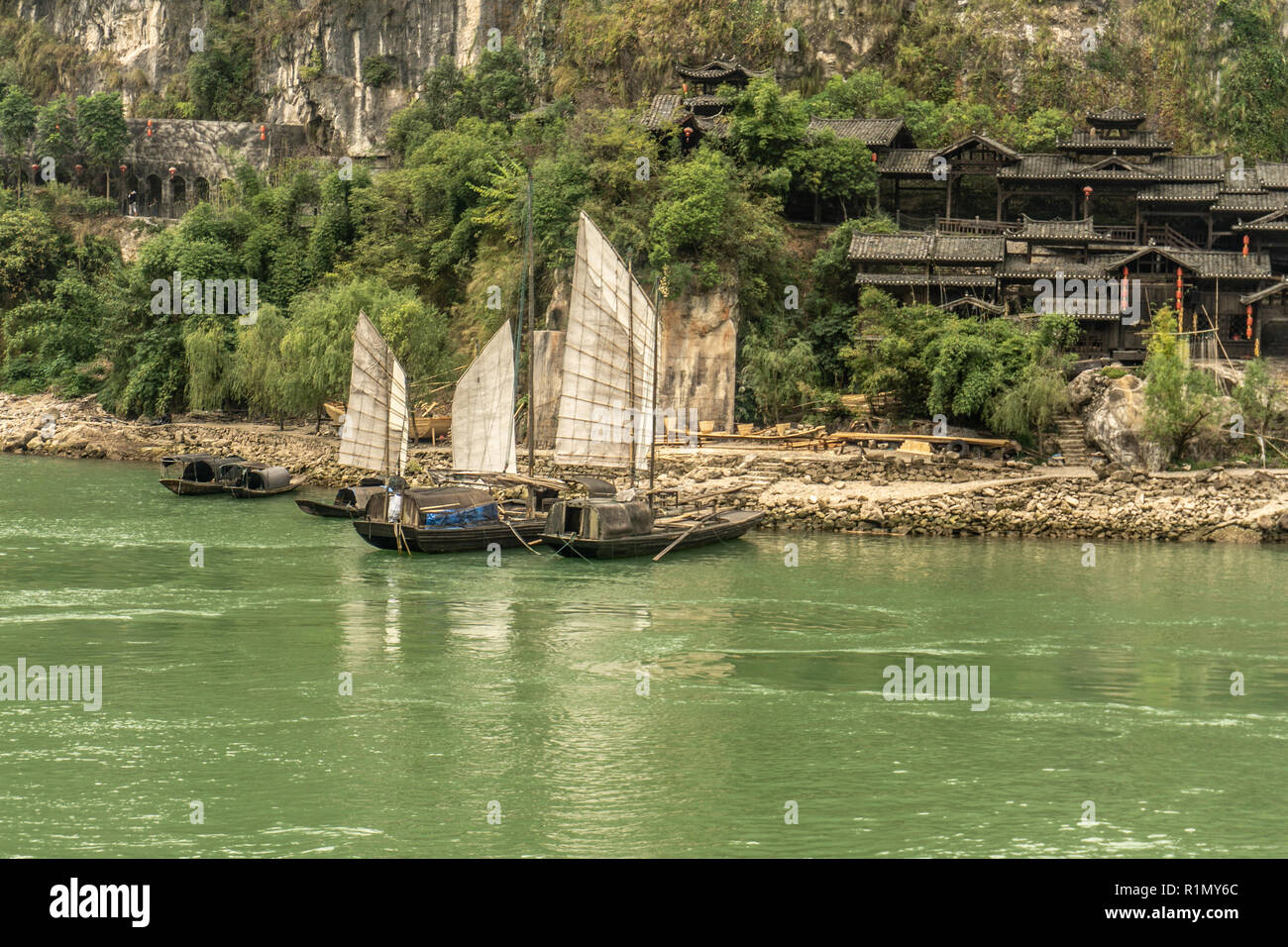 Sampans mit Segeln entlang des Jangtse-Flusses mit traditionellen Häuser im Hintergrund Stockfoto