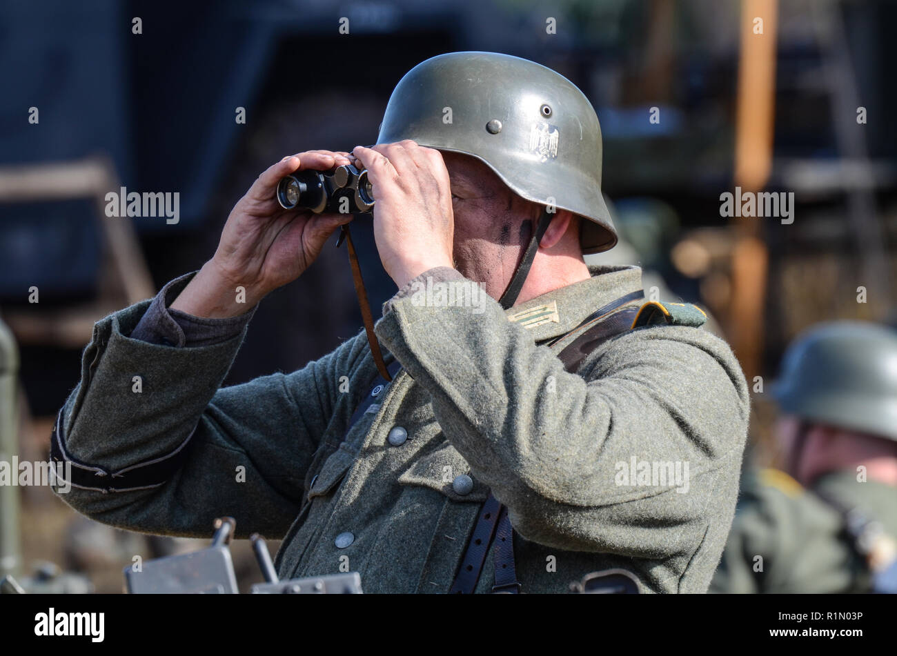 Reenactor, Nachstellung eines deutschen Soldaten aus dem Zweiten Weltkrieg, der durch ein Fernglas schaut. Infanteristen der Wehrmacht. Einheitlich Stockfoto