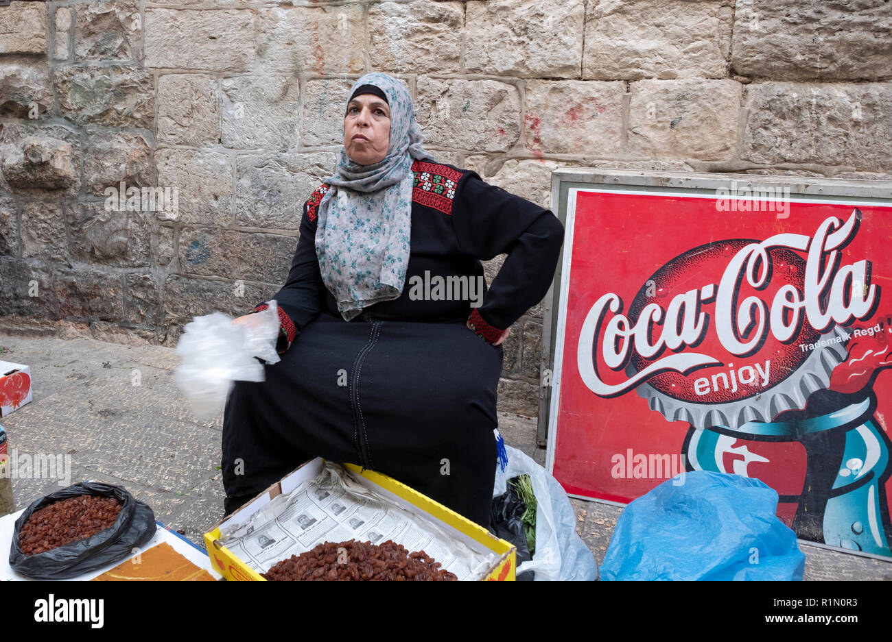 Eine muslimische Frau, die an einem Coca Cola Schild und Verkauf von getrockneten Früchten. In der alten Stadt, Jerusalem, Israel. Stockfoto