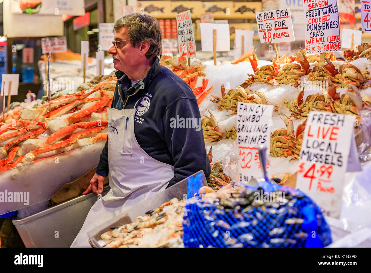 Seattle, Vereinigte Staaten - November 08, 2018: fischhändler an einem mit frischen Meeresfrüchten wie Krabben, Garnelen und Muscheln Stall für Verkauf am Pike Place Market Stockfoto