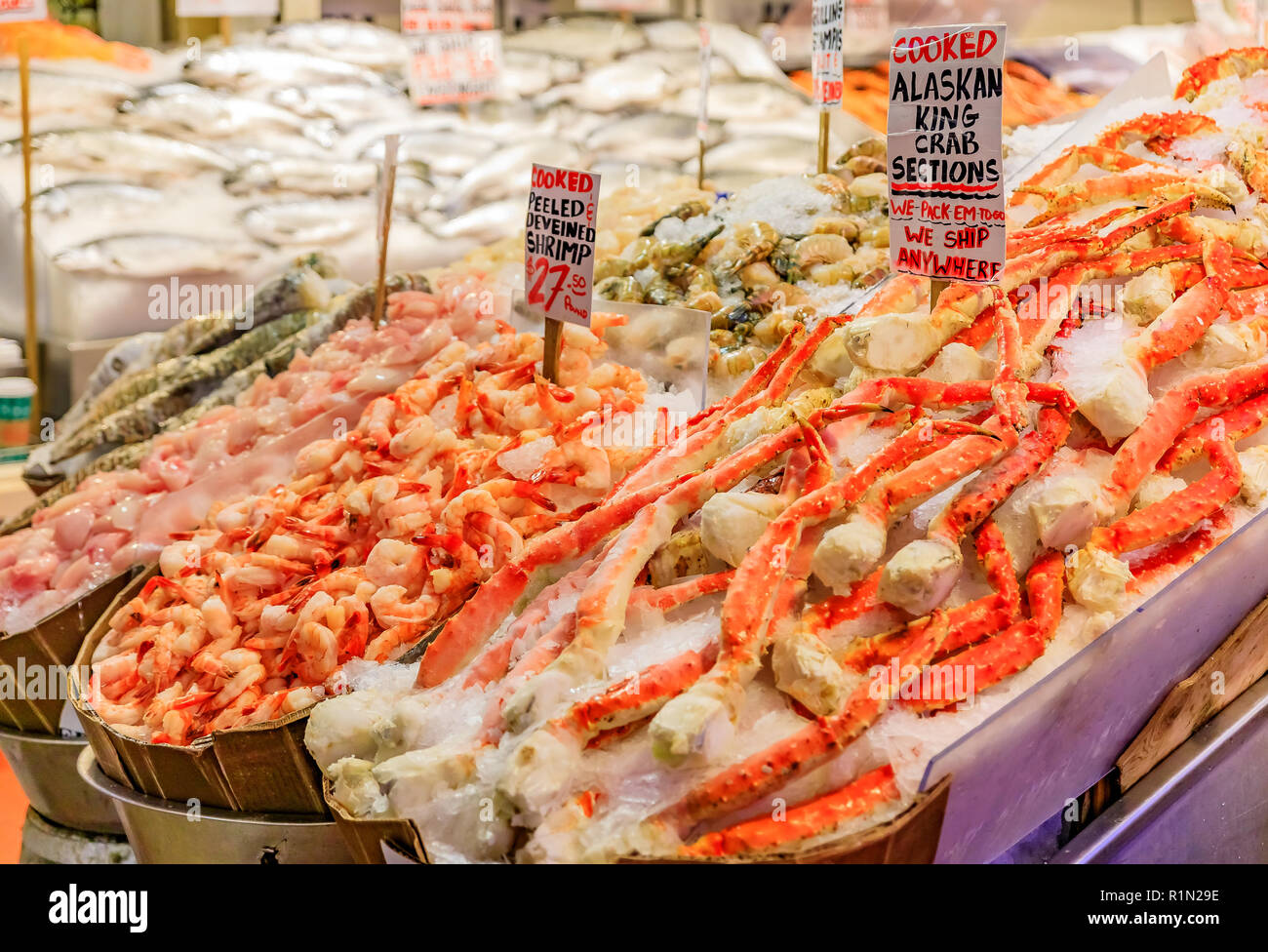 Fischhändler an einem mit frischen Meeresfrüchten wie Krabben und Garnelen Stall für Verkauf am Pike Place Market in Seattle, Washington Stockfoto