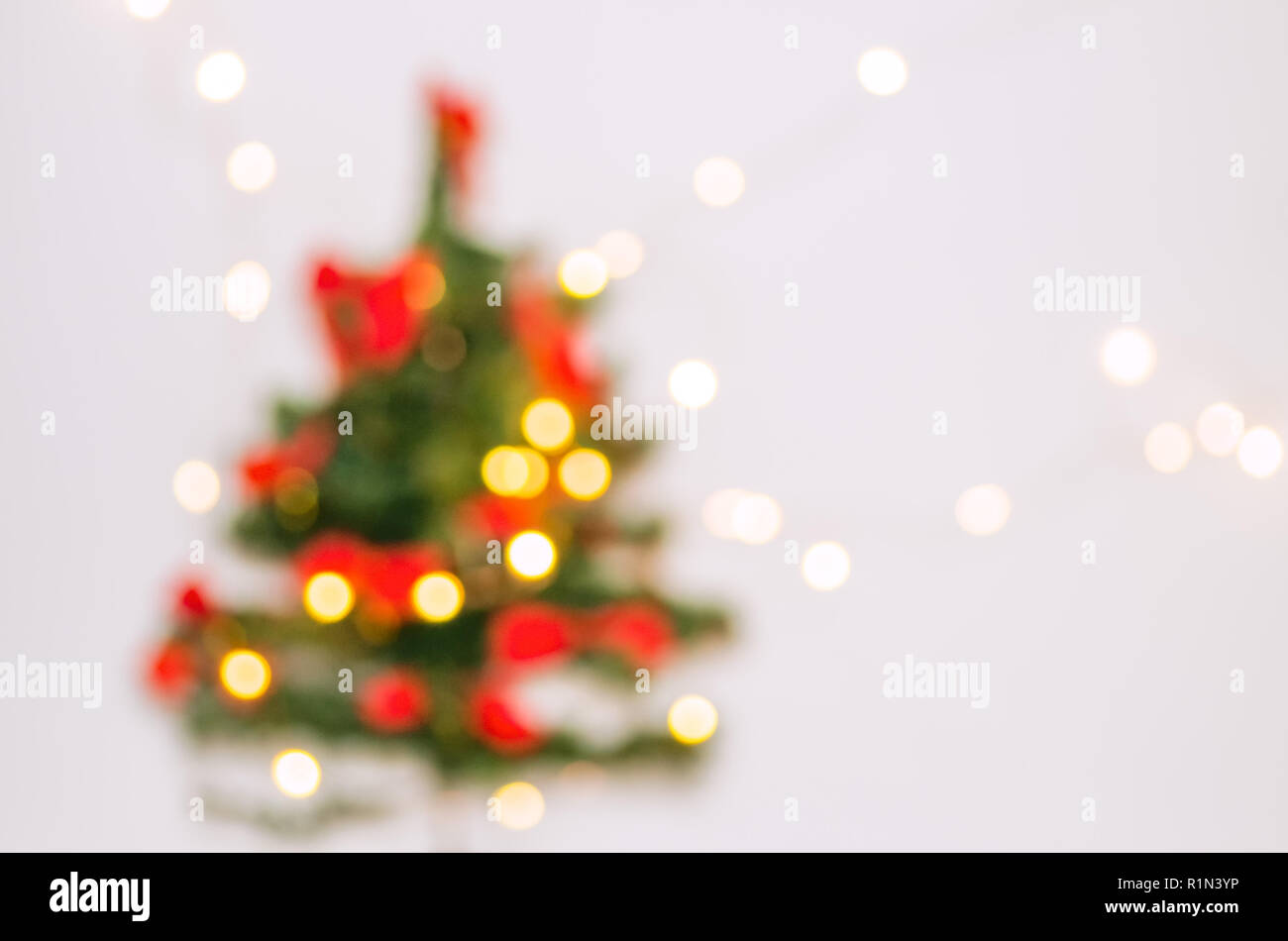 Unscharfer Hintergrund. Weihnachtsbaum auf einem weißen Hintergrund. Girlande, die an der Wand. Weihnachtsbaum in einem weißen Raum für Weihnachten. Stockfoto
