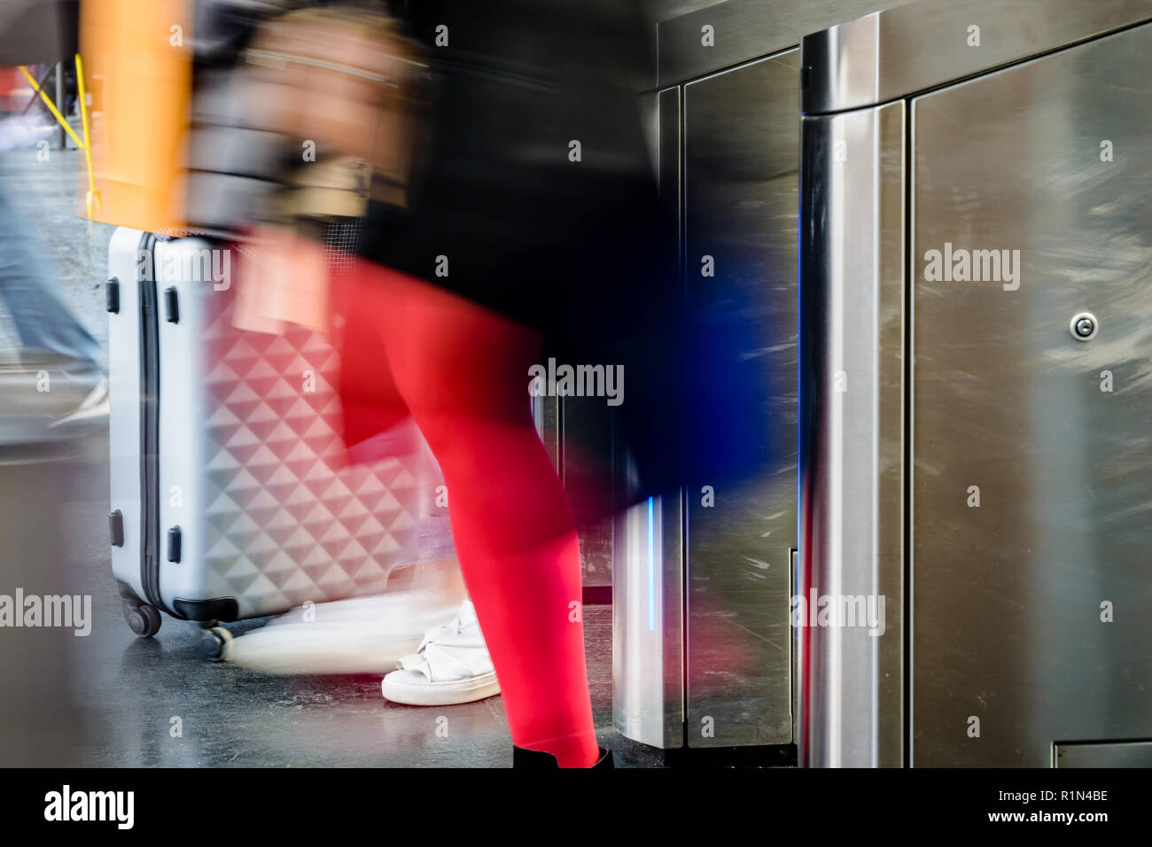 Seitliche Sicht auf Frauen mit rollenden Koffern durch Edelstahl ticket Tore in einem öffentlichen Verkehrsmittel Bahnhof in Paris mit Bewegungsunschärfe. Stockfoto