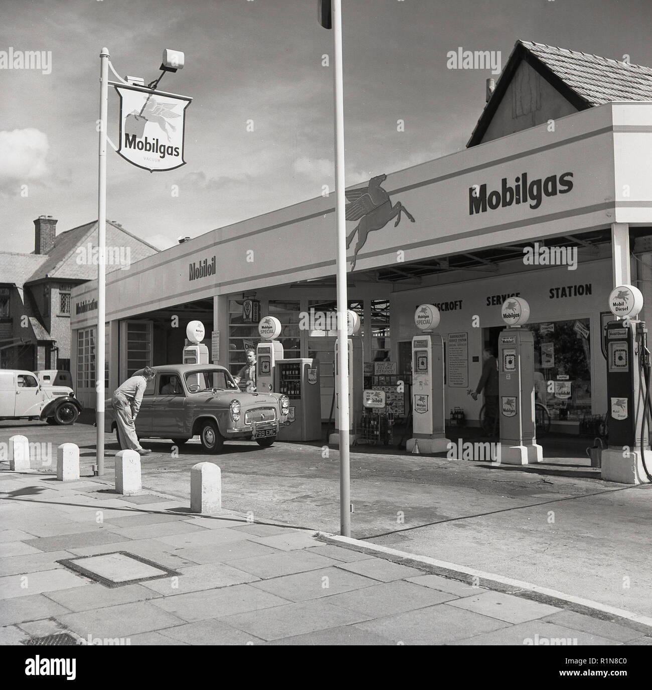 1950, historische, die goldenen Tage des Autofahrens, eine Tankstelle sttendant spricht mit einem Treiber eines Autos an den Zapfsäulen an der Mobilgas Ravenscroft Service Station auf der Great West Road, London, England, UK. Stockfoto