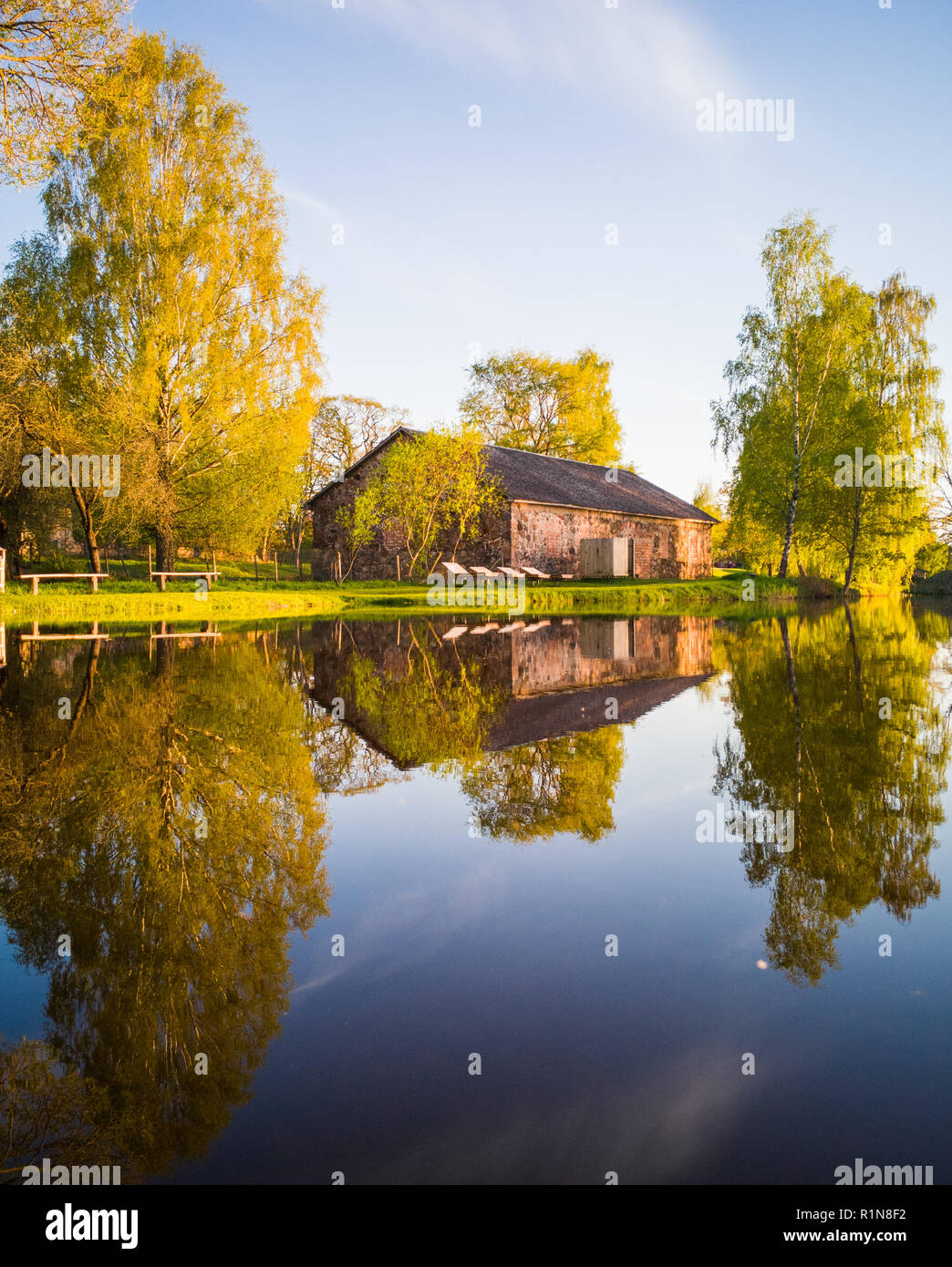 Schönen Baum Reflexion in den See auf einem sonnigen Frühling - Herbst Farben. Mit einem klaren, blauen Himmel über ihnen-symmetrische Reflexion Stockfoto