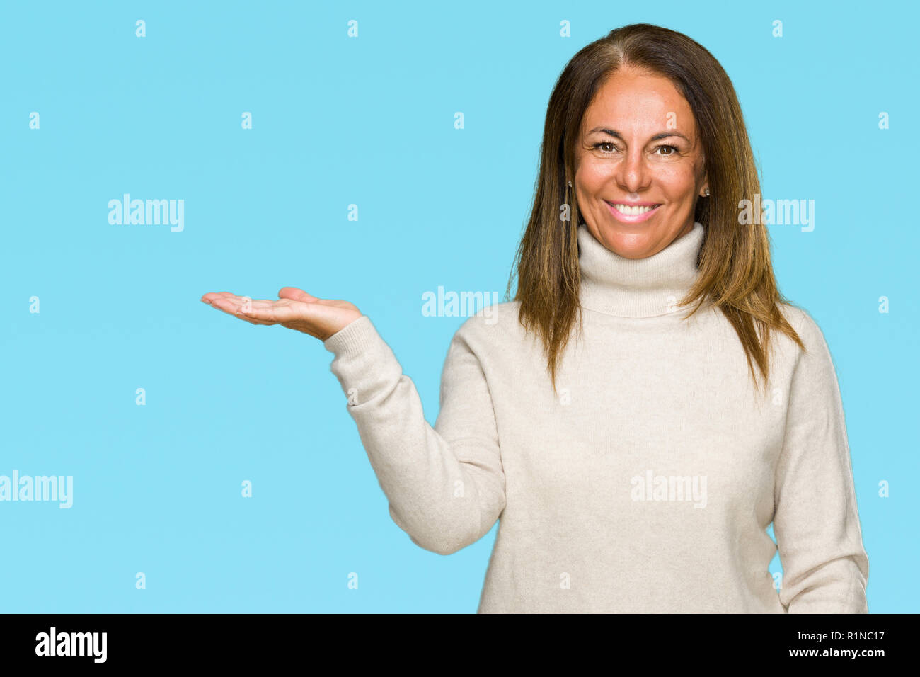 Schönen mittleren Alter erwachsene Frau tragen winter Pullover über isolierte Hintergrund lächelt fröhlich präsentieren und zeigen mit der Handfläche auf Stockfoto