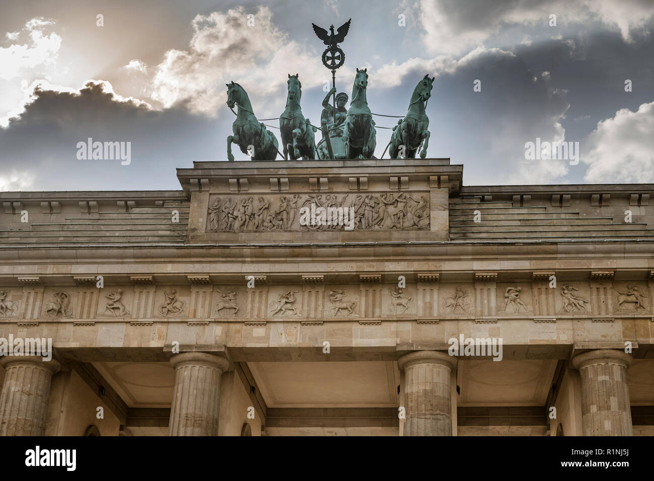 Die historische Quadriga auf dem Brandenburger Tor in Berlin sitzt vor einem dramatischen stürmischen Himmel in der Abenddämmerung. Stockfoto