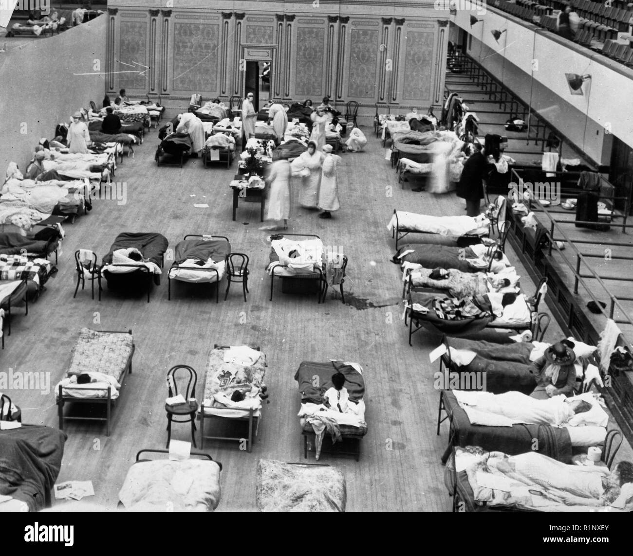 1918 Grippe Epidemie: die Oakland Municipal Auditorium im Einsatz als provisorisches Krankenhaus. Das Foto zeigt freiwillige Krankenschwestern aus dem Amerikanischen Roten Kreuz neigend Grippe Erkrankten in der Oakland Auditorium, Oakland, Kalifornien, während der Grippepandemie von 1918. Stockfoto