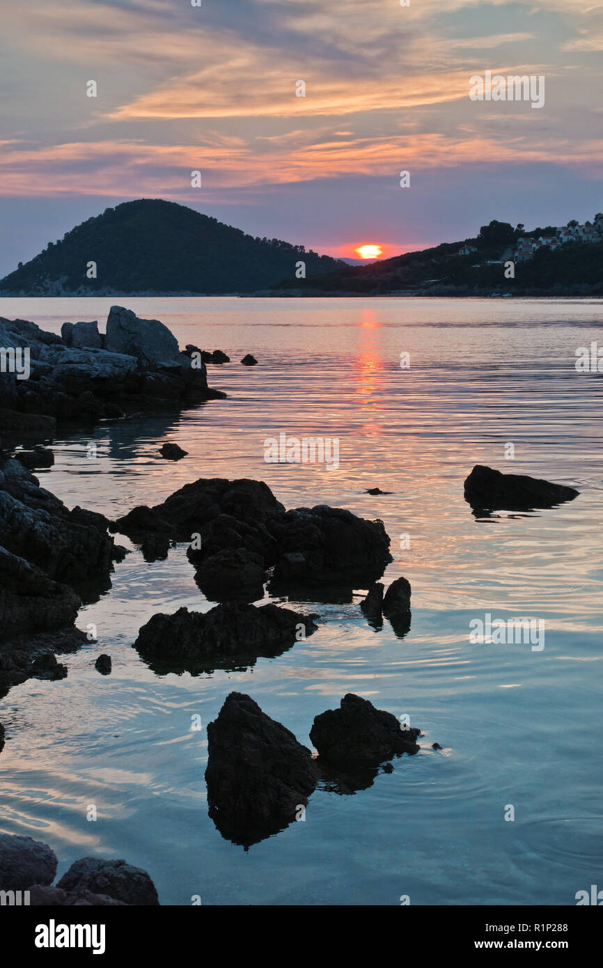 Felsige Küste und im ruhigen Wasser der Bucht Panormos bei Sonnenuntergang, Insel Skopelos, Griechenland Stockfoto