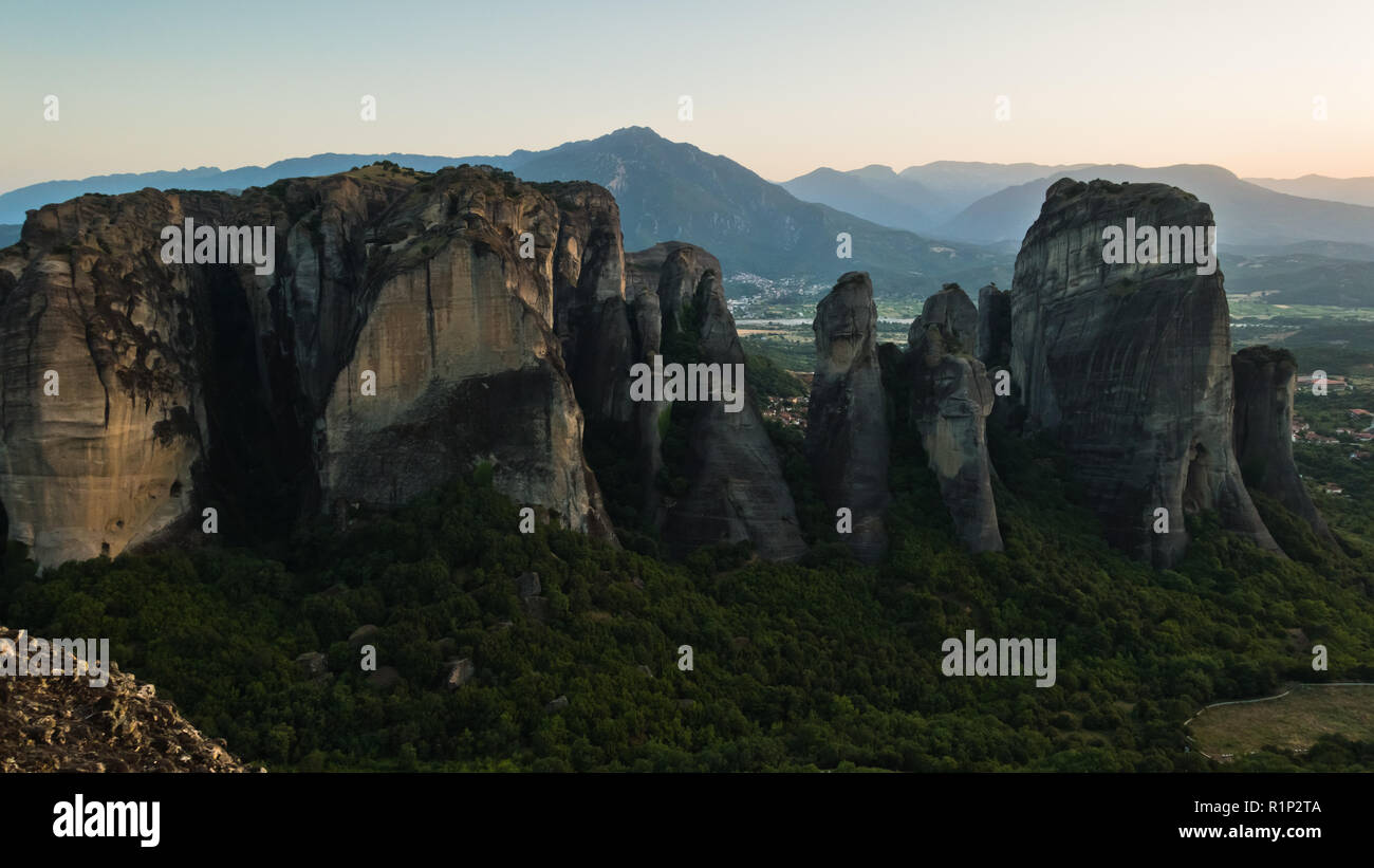 Die riesigen Felsen mit den Klöstern und Sonnenuntergang hinter die Berge in der Ferne in Meteora, Thessalien, Griechenland Stockfoto