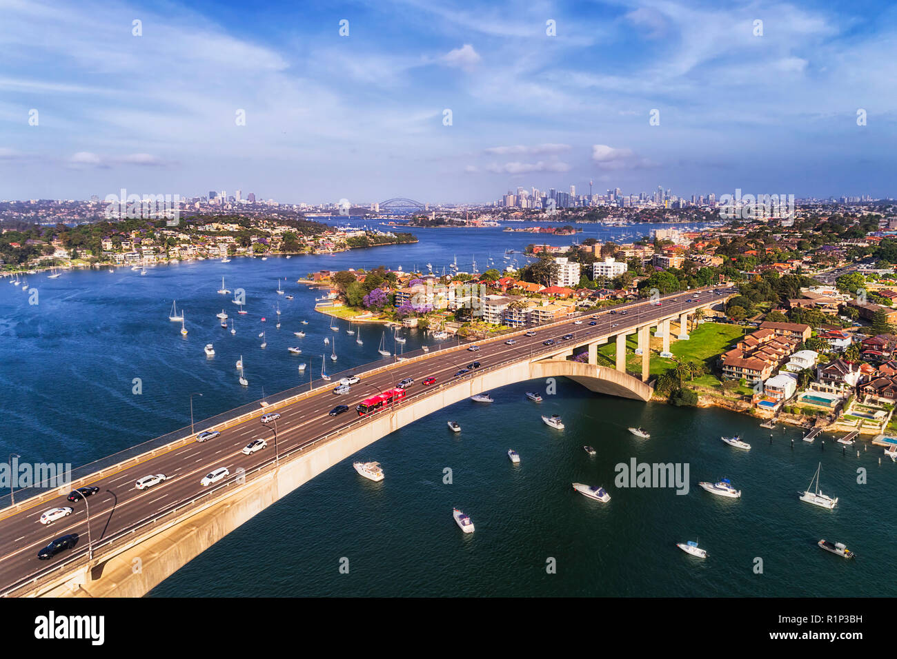 Kfz-Verkehr auf mehrspurigen Gladesville im Hinblick auf die Stadt Sydney CBD auf Horizont von Parramatta River mit Boote und Yachten. Stockfoto