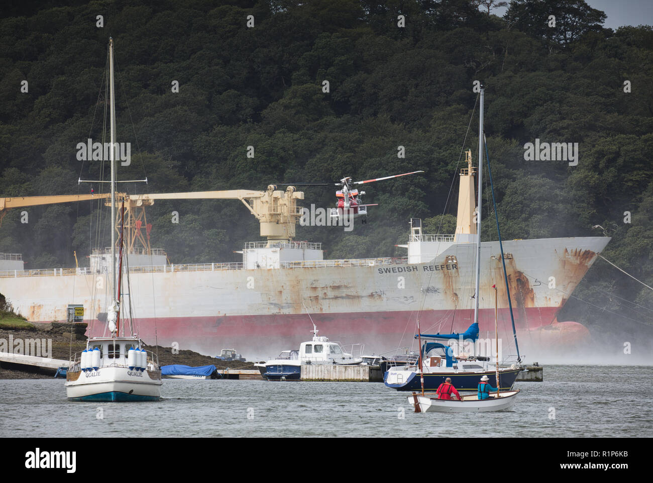 Küstenwache schwebenden Hubschrauber über dem Tanker und ein Hubschrauber Crewmitglied down Winched wird der Unfall zu helfen. River Fal, Cornwall. Stockfoto