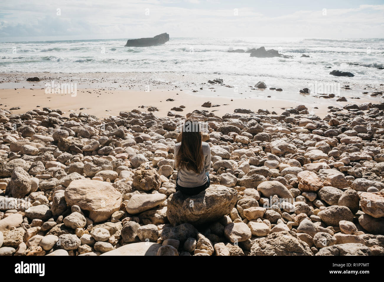 Das Mädchen in der Einsamkeit bewundert einen schönen Blick auf den Atlantik in Portugal. Suche nach Seele oder die Einheit mit der Natur. Stockfoto