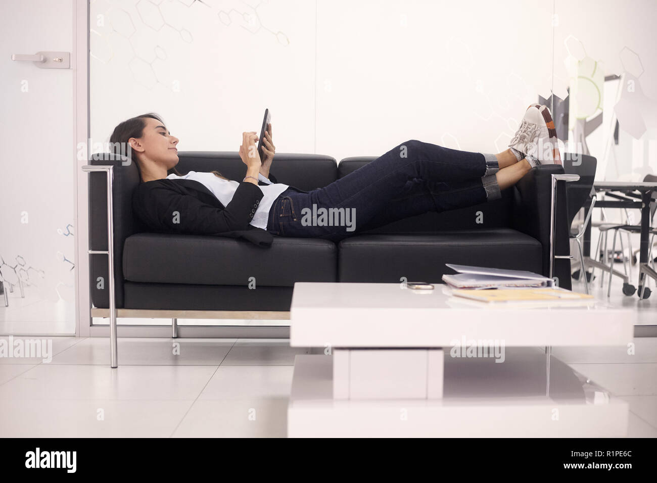 Eine junge Frau, white-collar worker, Relaxen auf dem Sofa, Arbeiten auf Tablet in modernen Büro zuhause. Stockfoto