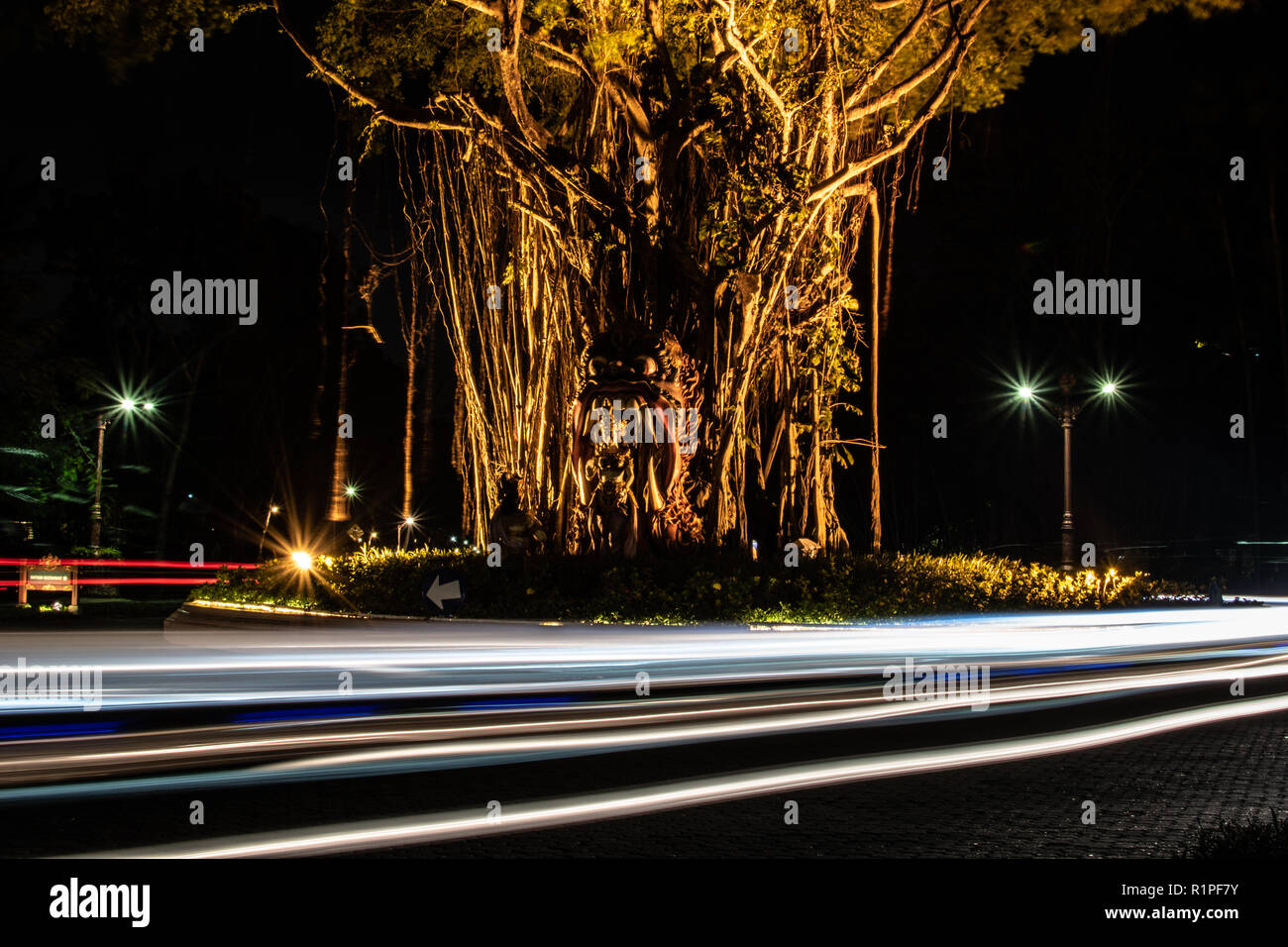 Verschwommene Bewegung eines Lichtstrahls auf der Straße neben dem Chimärischen indonesischen Baum. Interessante und abstrakte Lichter in Orange, die als Hintergrund oder Textur verwendet werden kann. Stockfoto