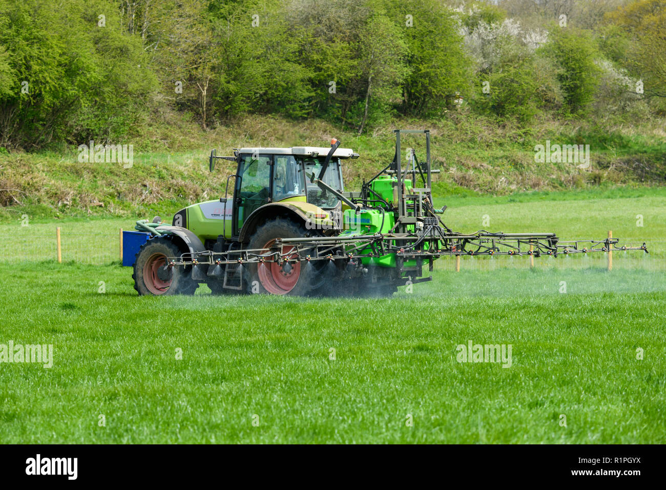 Landwirt Besetzt bei der Arbeit auf der Farm, Fahren des Traktors spritzen Erntegut auf Ackerland, mit Ausleger Sprüher Chemikalien - North Yorkshire, England, UK zu verteilen. Stockfoto