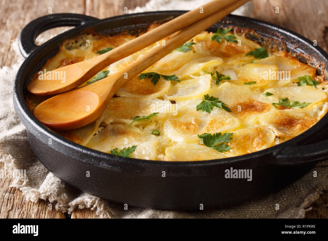 Köstliche Finnische gebackene Kartoffeln mit Sardellenfilets, Zwiebeln und Sahne close-up in einer Pfanne. Horizontale Stockfoto