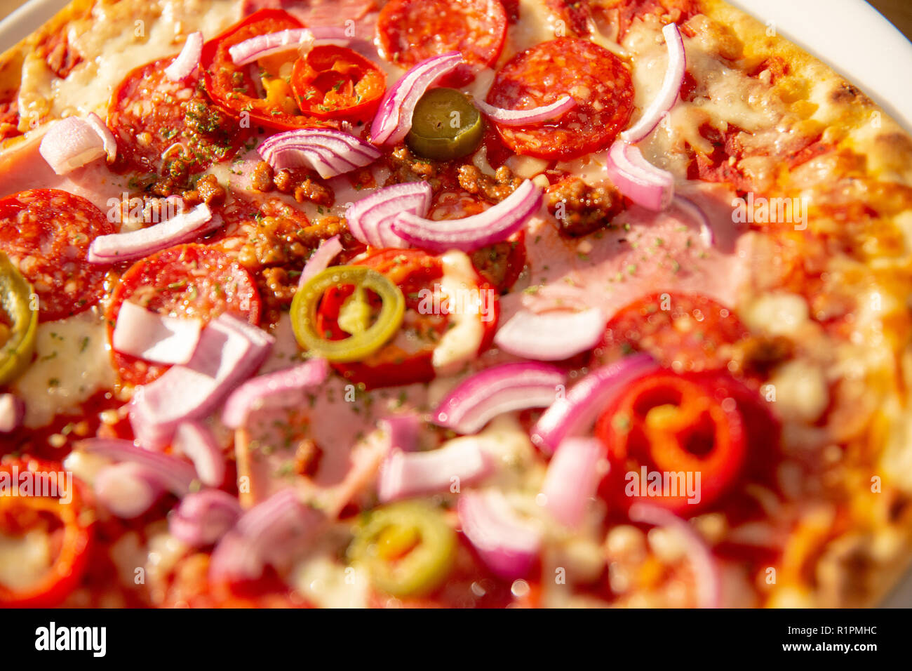 Würzig, frischen dünne Kruste Pizza - jalepenos, würziges Rindfleisch, Peperoni, roten Zwiebeln, Nahaufnahme food Fotografie mit unscharf Elemente Stockfoto