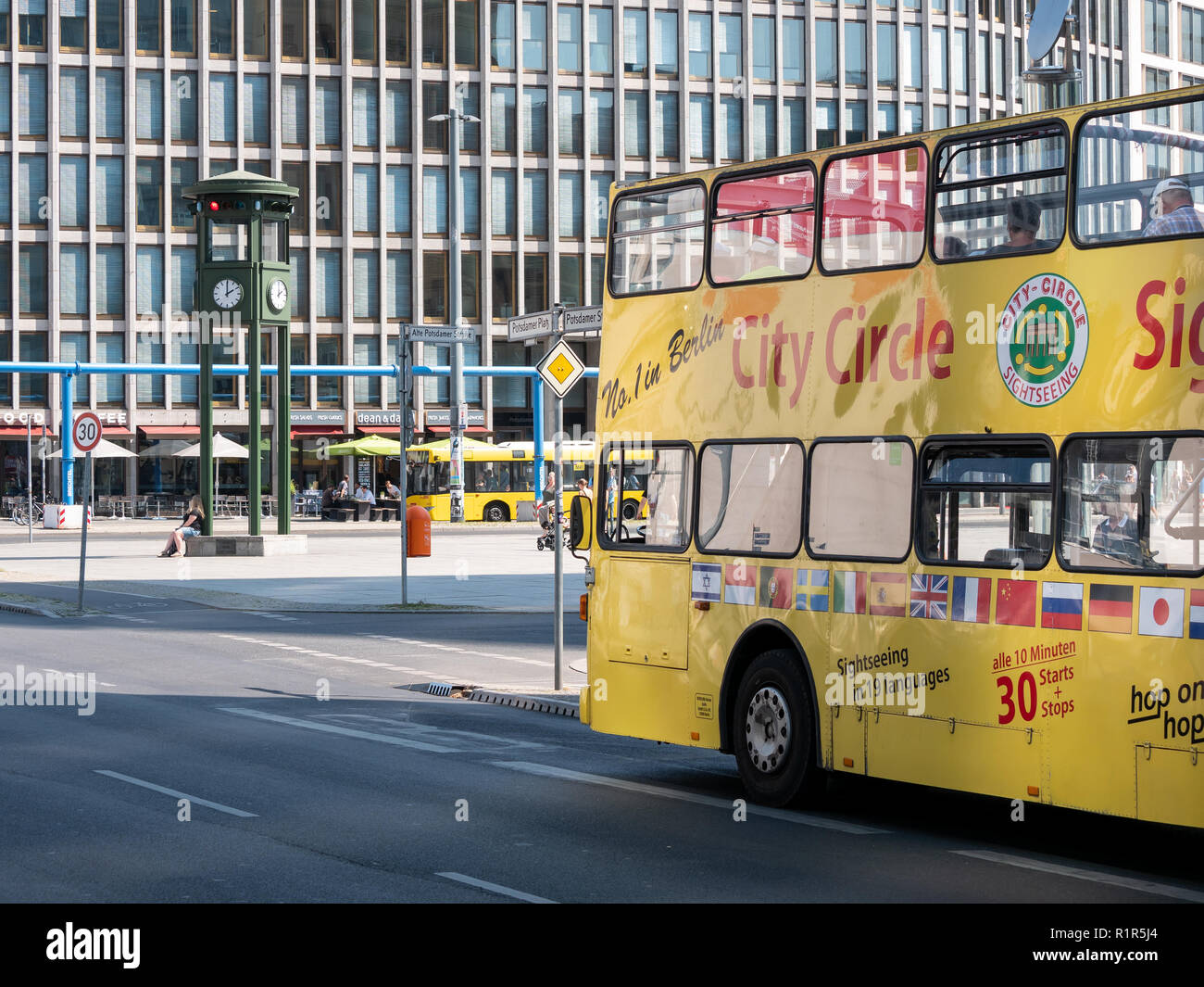 BERLIN, DEUTSCHLAND - 3. AUGUST 2018: Gelbe Tourist Bus am berühmten Potsdamer Platz mit Uhr im Hintergrund in Berlin, Deutschland Stockfoto