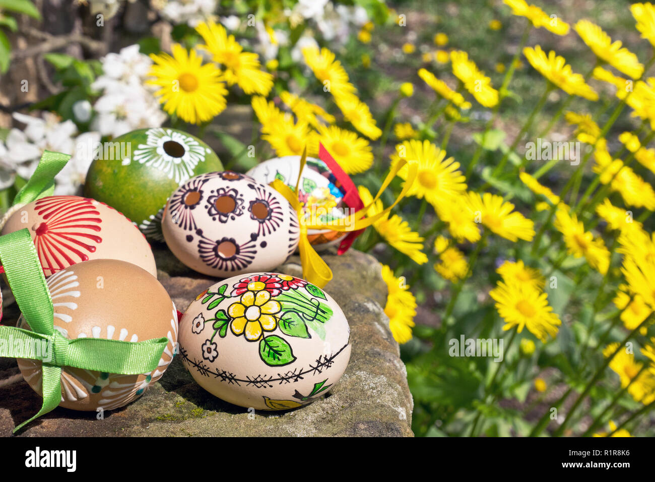 Bemalte Ostereier mit gelben Blumen im Garten Stockfoto