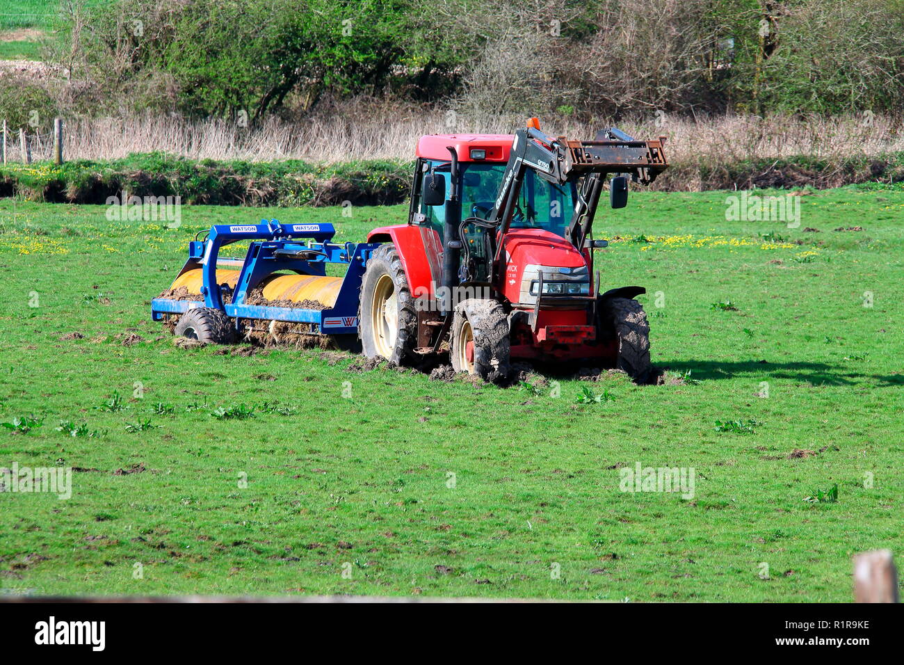 Schöne neue rote Traktor abschleppen eines sehr schweren Gras