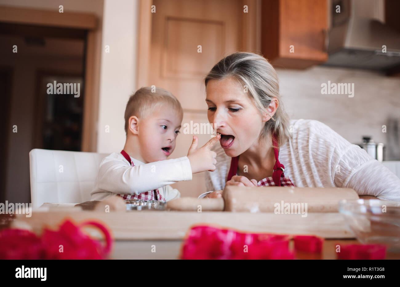 Ein behinderter Down-syndrom Junge mit seiner Mutter zuhause Backen. Stockfoto