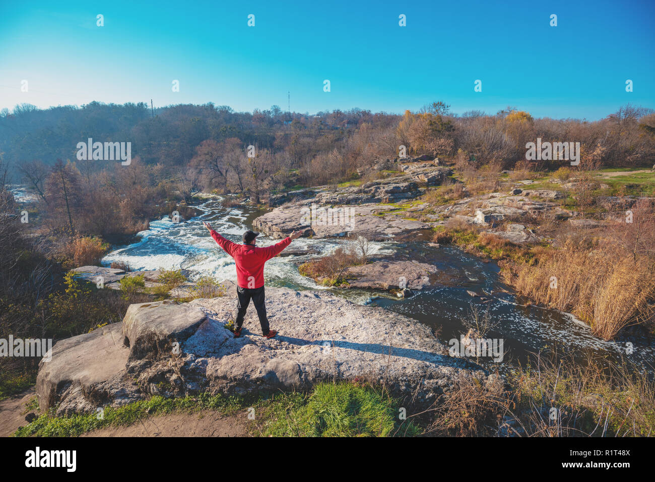 Ein Mensch steht auf den Felsen der Schlucht mit den Händen in der Luft im Herbst Stockfoto