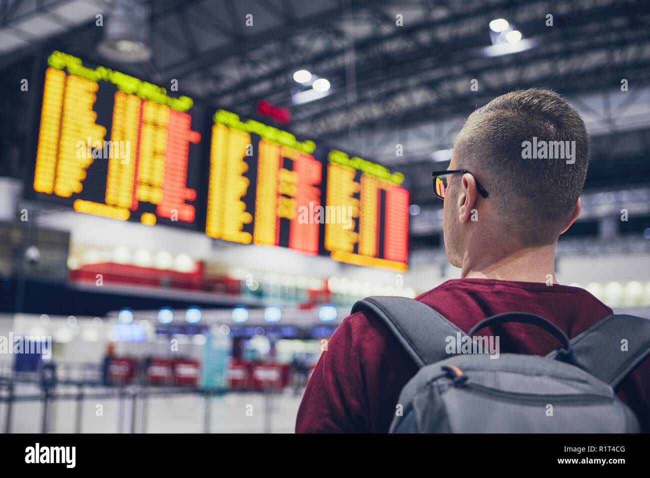 Ansicht der Rückseite des jungen Mannes Kontrolle Flugplan auf der Anreise Abreise am Flughafen. Stockfoto
