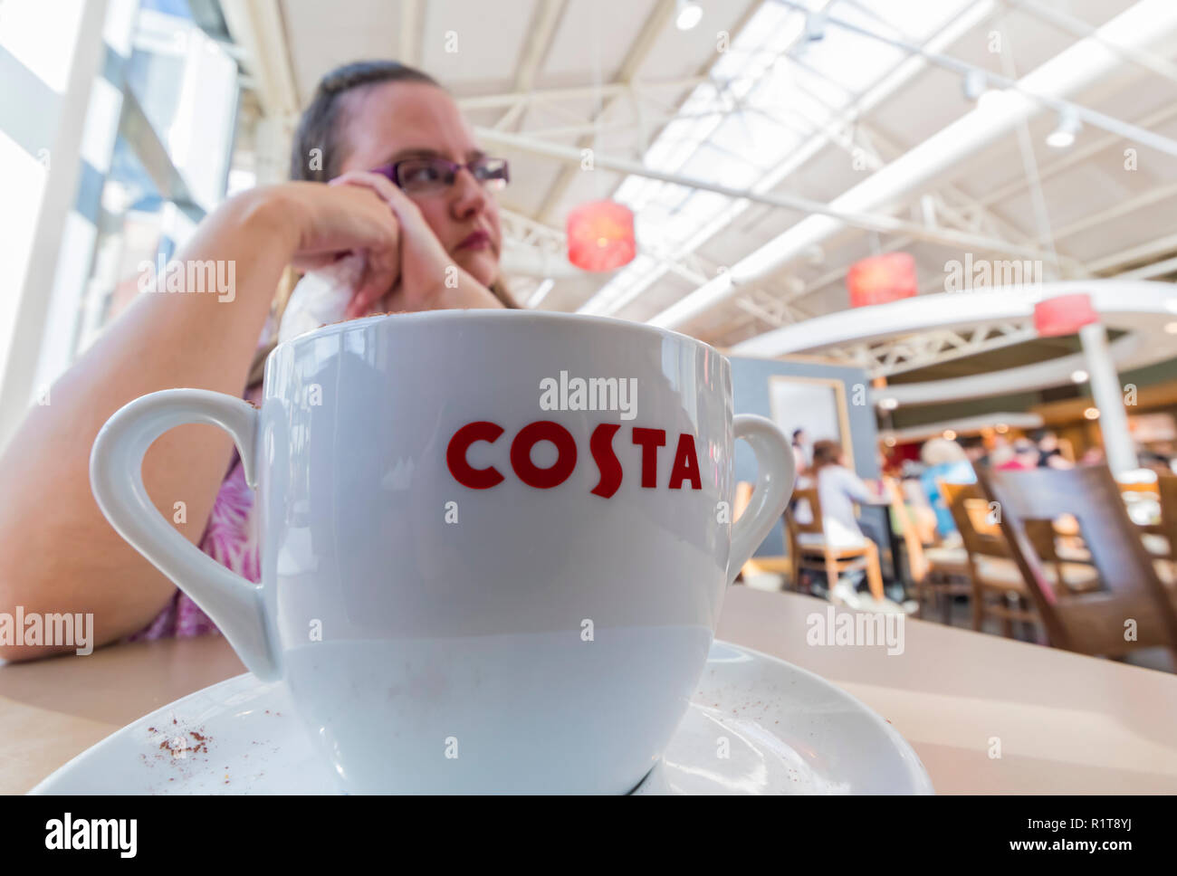 Frau sitzt Trinken eine große Tasse Kaffee an einem Costa Cafe in England, Großbritannien. Stockfoto