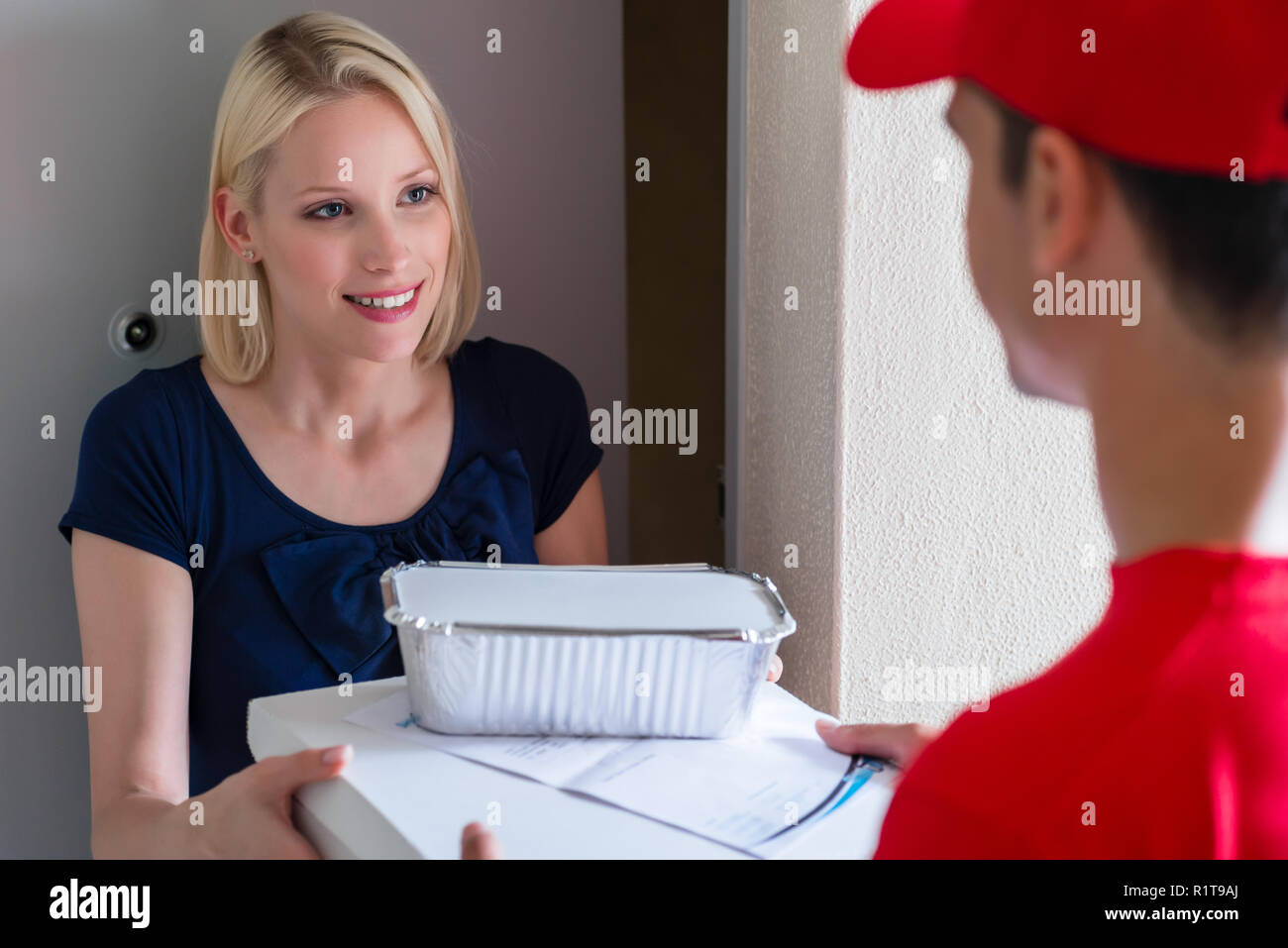 Gerne blonde junge Frau, Fast Food Delivery Man bestellen Stockfoto