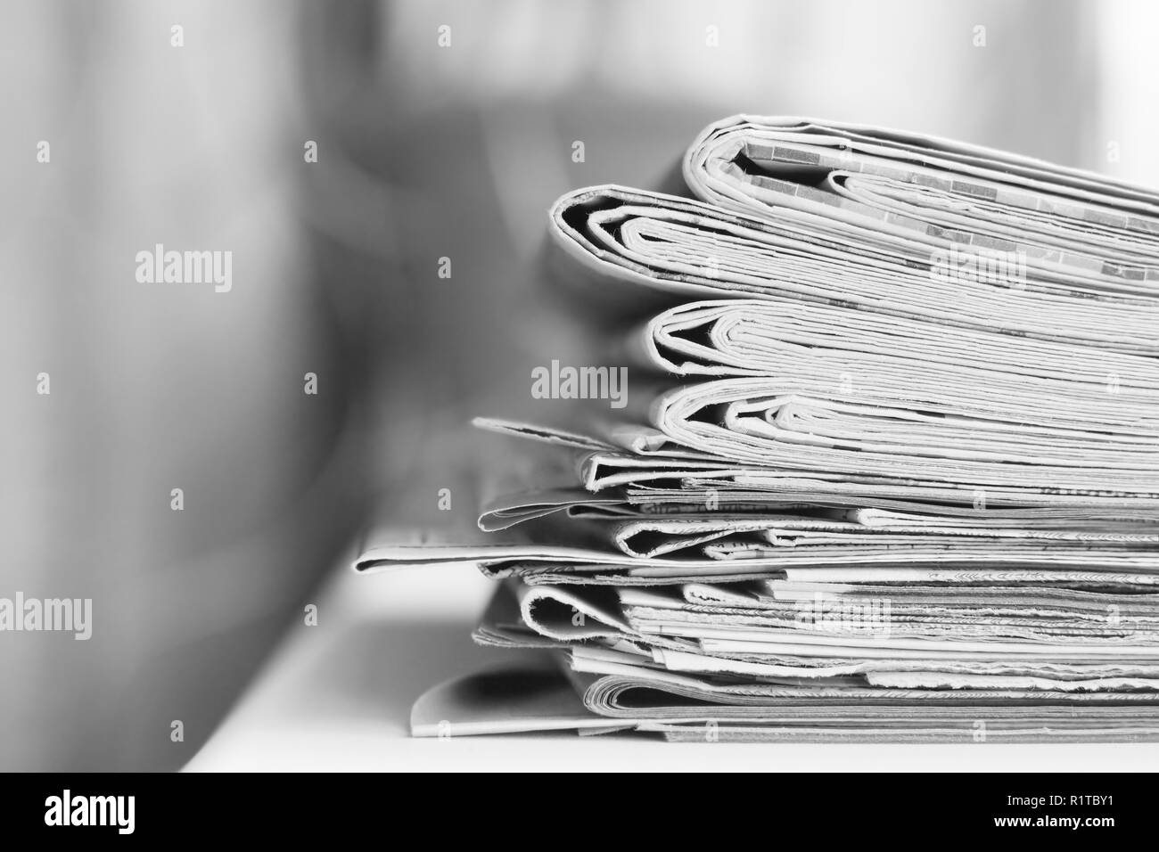 Viele Zeitungen in Haufen gegen verschwommenen Hintergrund mit leeren Raum für Text oder Zeichen gestapelt Stockfoto