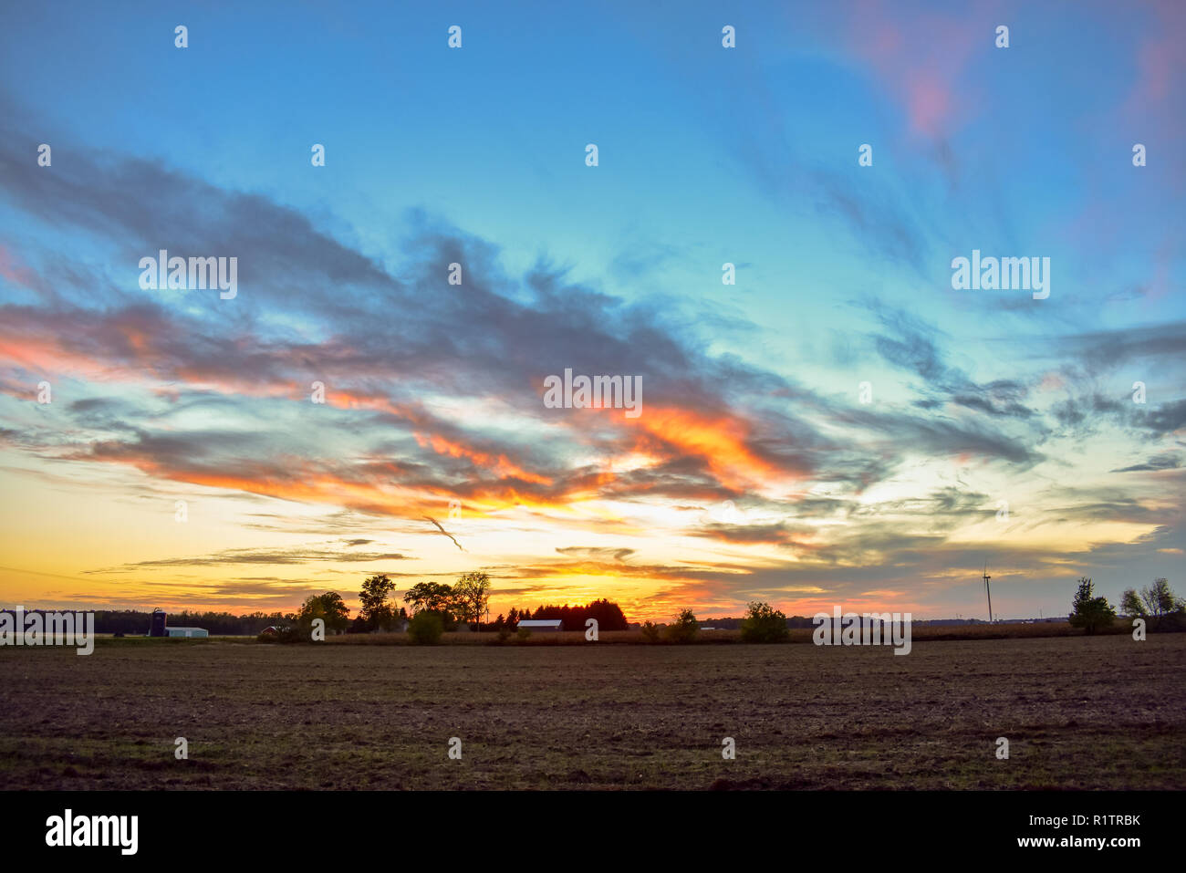 Sonnenuntergang im ländlichen mittleren Westen, Michigan. Das Ackerland im Vordergrund war ein Weizenfeld und außerdem können Sie eine cornfield fast zur Ernte bereit. Stockfoto