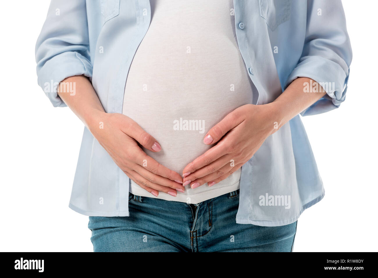 7/8 shot der schwangeren Frau in Jeans und Shirt holding Bauch mit Händen isoliert auf weißem Stockfoto