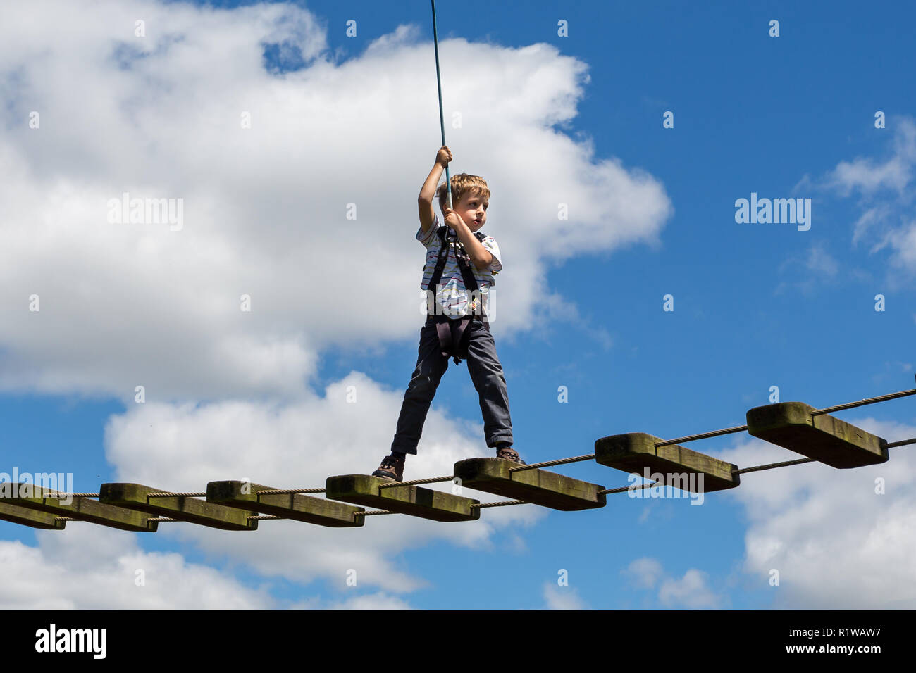 Little Boy unsicher auf High Wire mit nervösen Blick gegen den blauen bewölkten Himmel in Bristol, UK am 5. Juli 2016 ausgeglichen Stockfoto