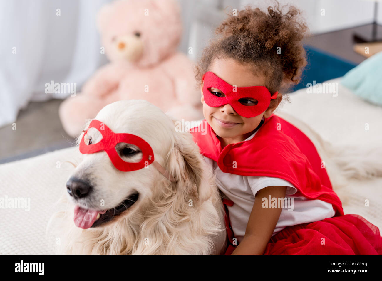 Lächelnd entzückenden kleinen afrikanischen amerikanischen Kid mit Happy Dog rot Superhelden Maske Stockfoto