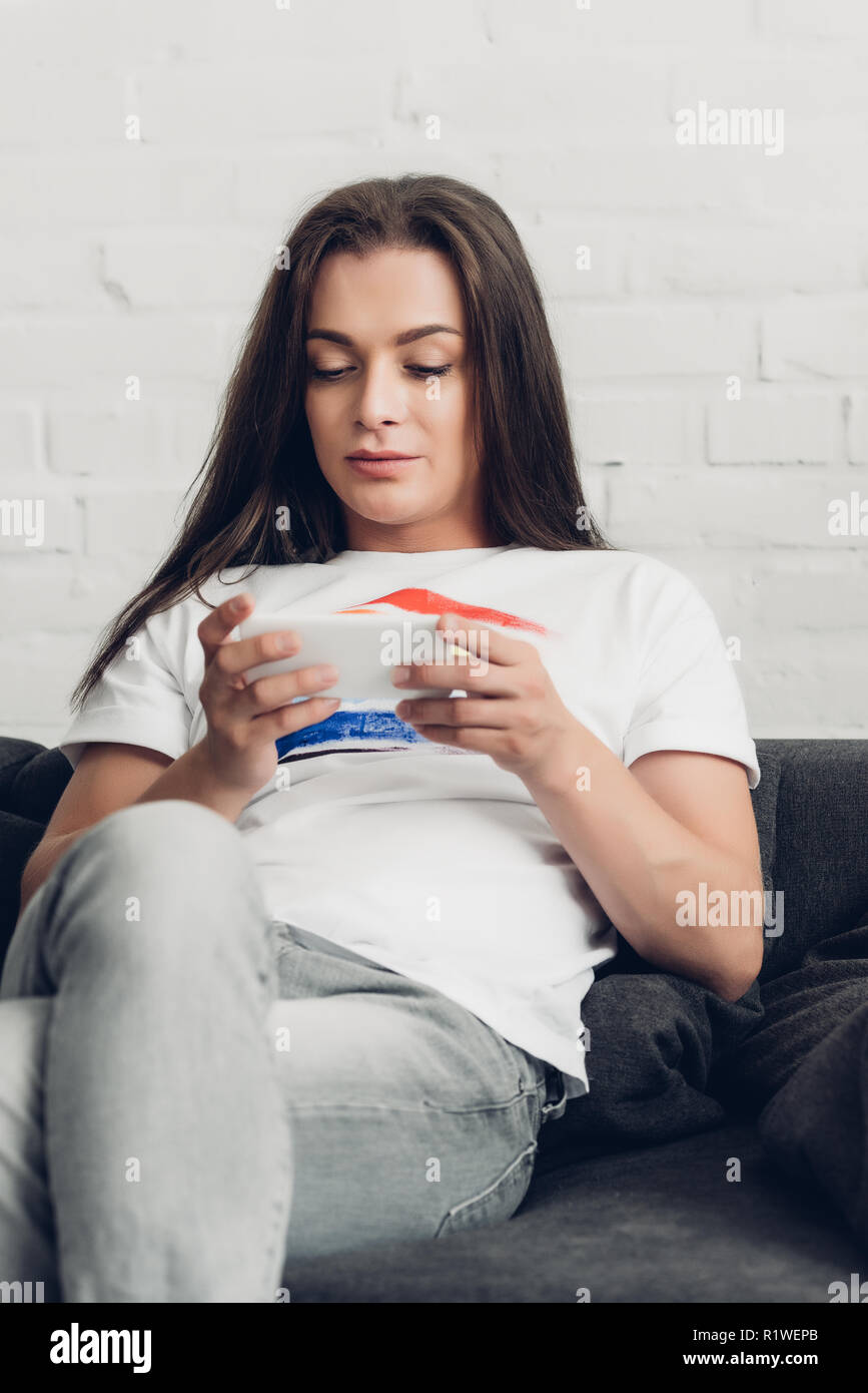 Junge transgender Menschen mit Smartphone auf der Couch zu Hause Stockfoto