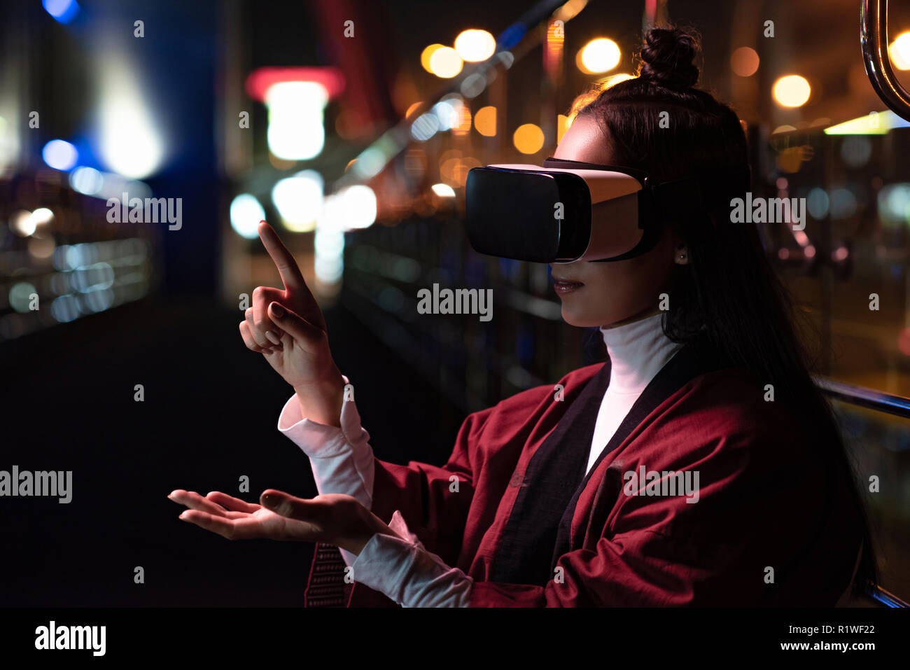Attraktiven asiatischen Mädchen mit Virtual reality Headset und verweist auf etwas, das auf der Straße in Abend, Stadt der Zukunft Konzept Stockfoto