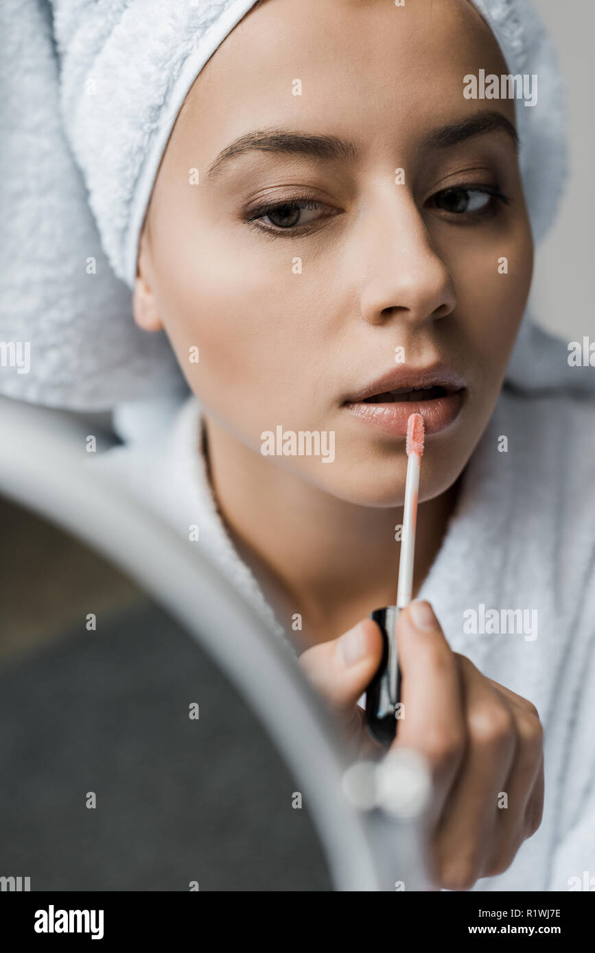 Attraktive junge Frau Anwendung Lip Gloss und Spiegel Stockfoto