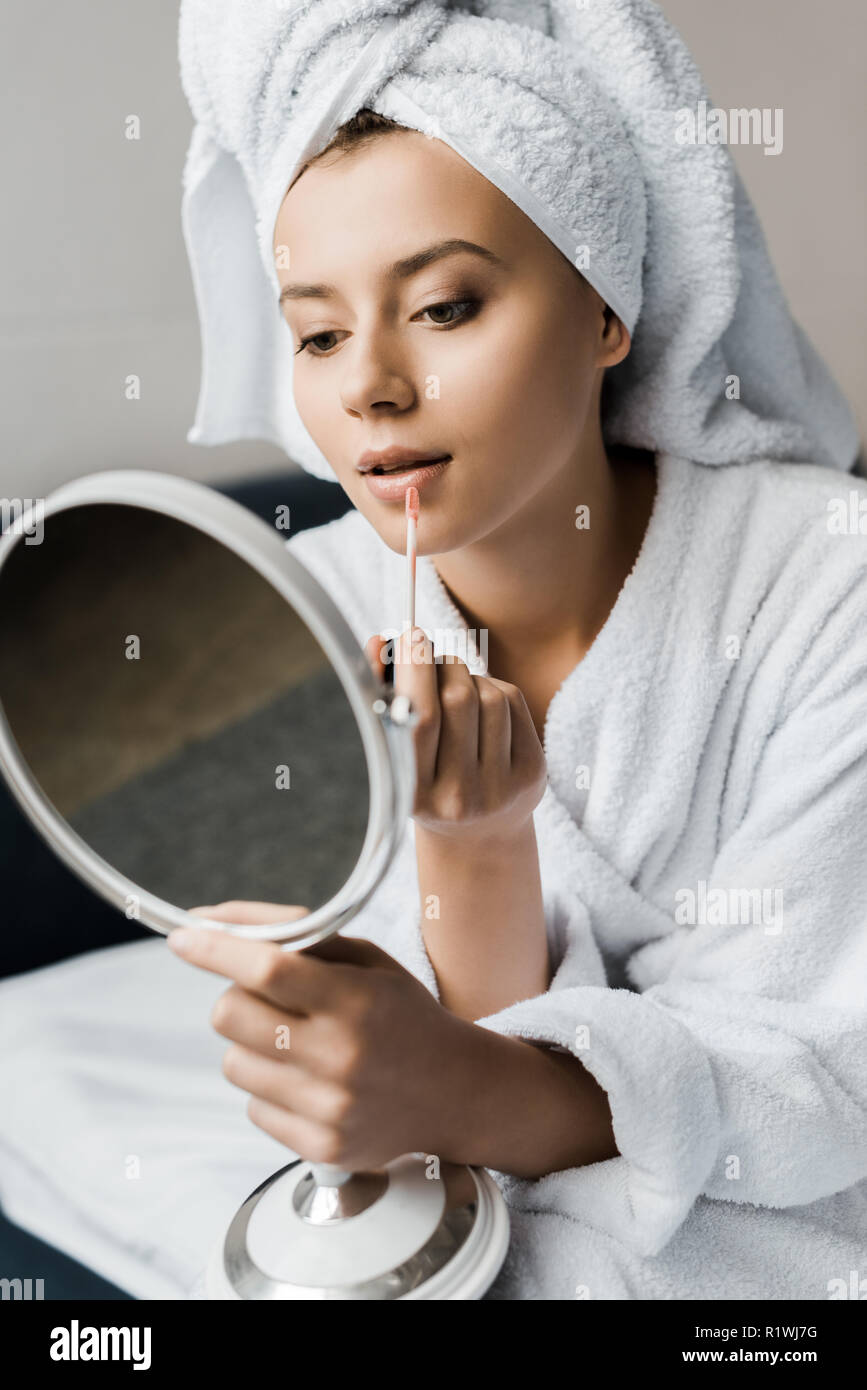 Attraktive Mädchen in Bademantel, Lip Gloss und Spiegel Stockfoto