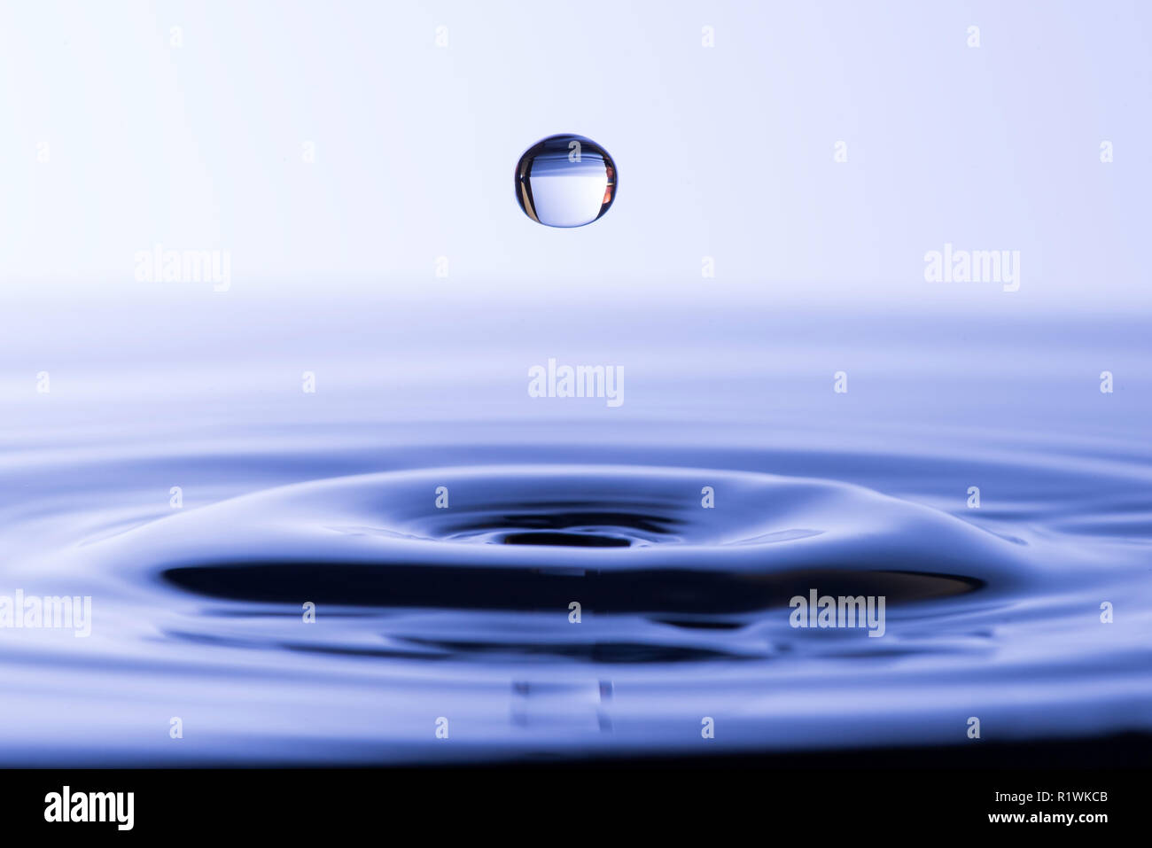 Wassertropfen fallen ins Wasser, wodurch eine konzentrische Kreise Stockfoto