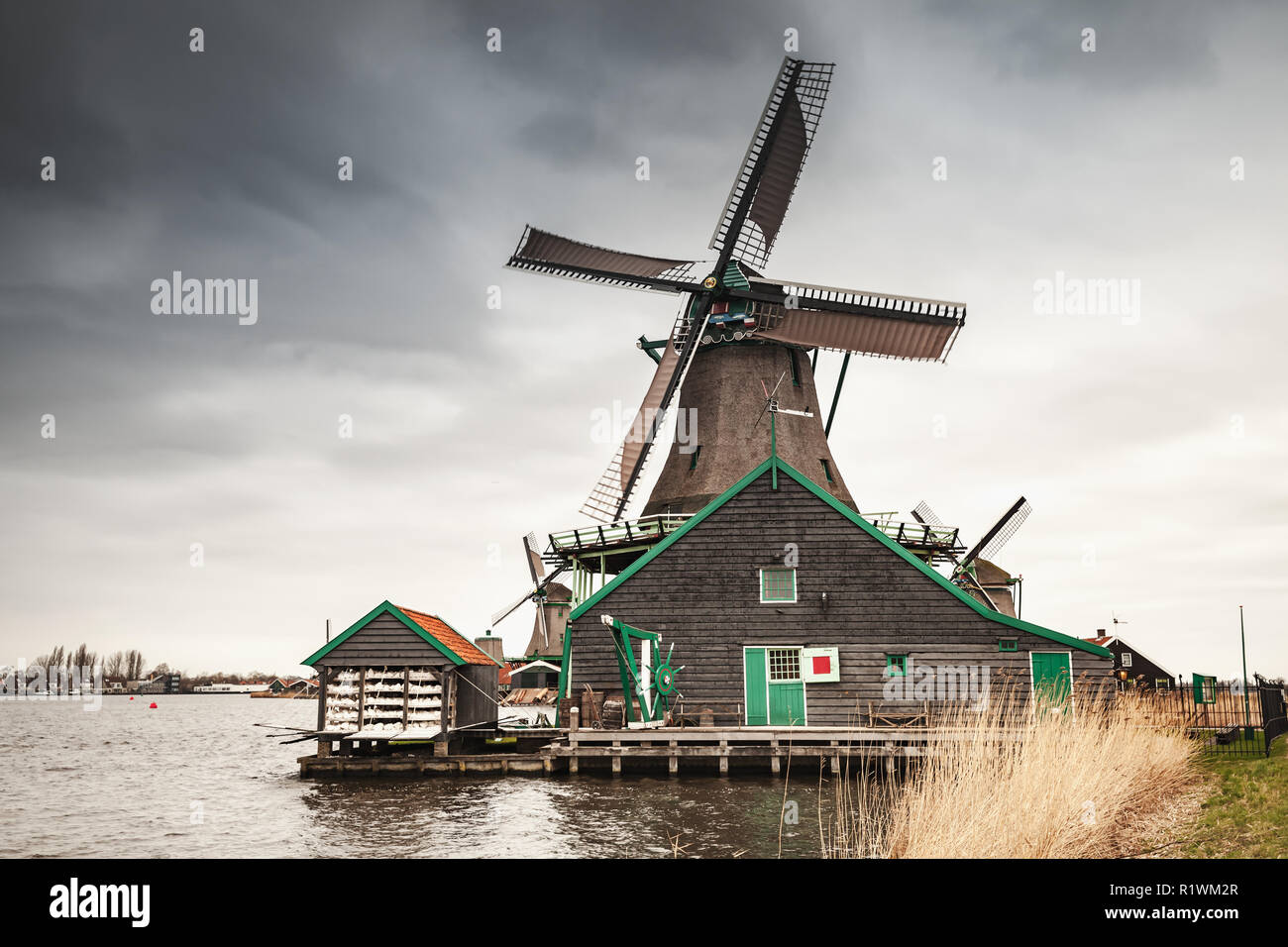 Alte Windmühle aus Holz Fluss Zaan Küste, Zaanse Schans Stadt, beliebten touristischen Attraktionen der Niederlande. Vorort von Amsterdam Stockfoto