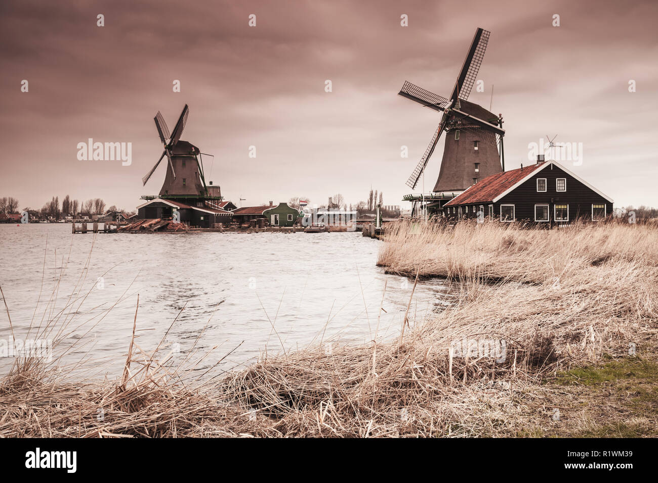 Holz- Windmühlen auf Fluss Zaan Küste, Zaanse Schans Stadt, beliebten touristischen Attraktionen der Niederlande. Vorort von Amsterdam. Foto mit warmen gradien Stockfoto