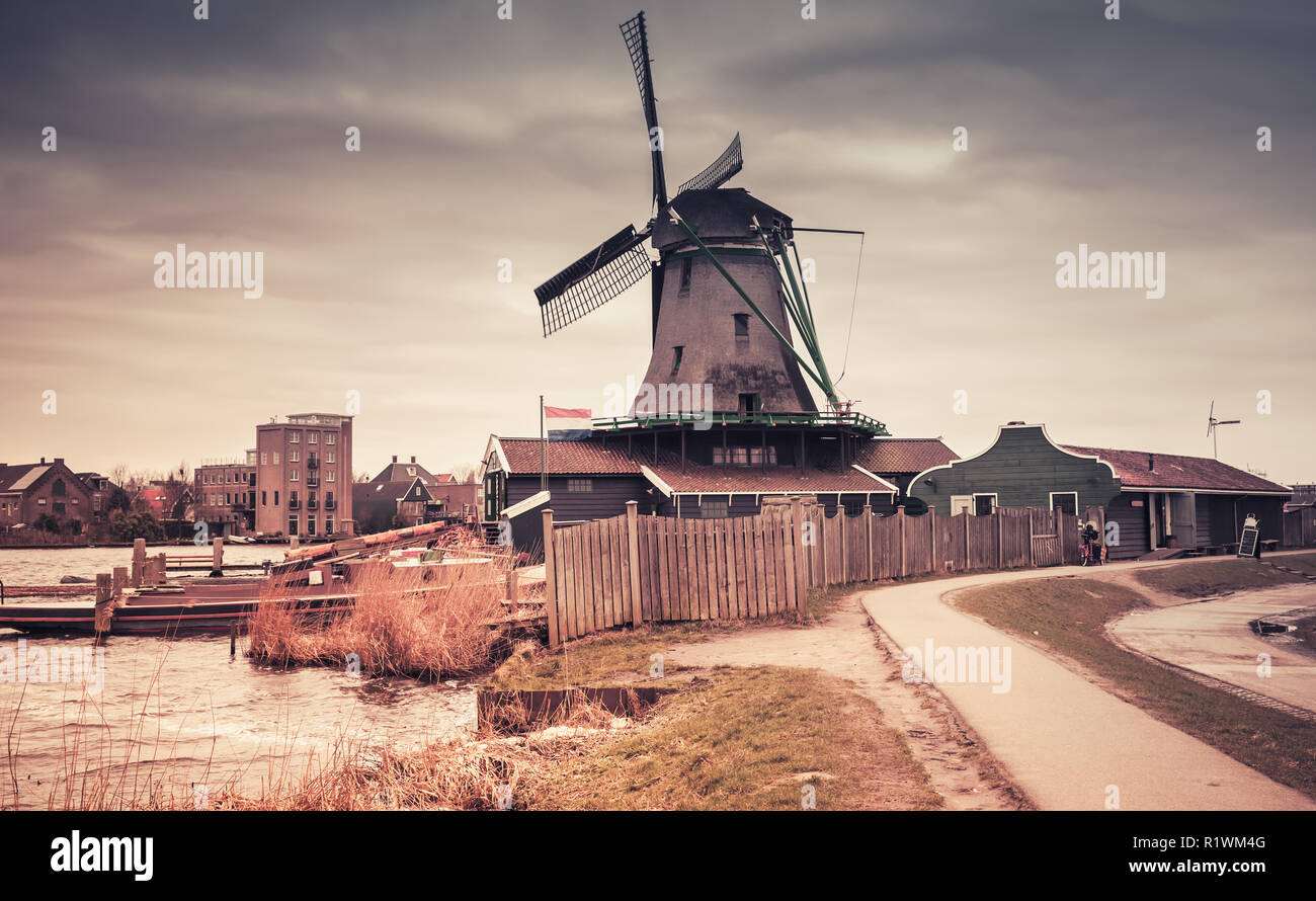 Alte Windmühle aus Holz Fluss Zaan Küste, Zaanse Schans Stadt, beliebten touristischen Attraktionen der Niederlande. Vorort von Amsterdam. Foto mit Farbverlauf Stockfoto