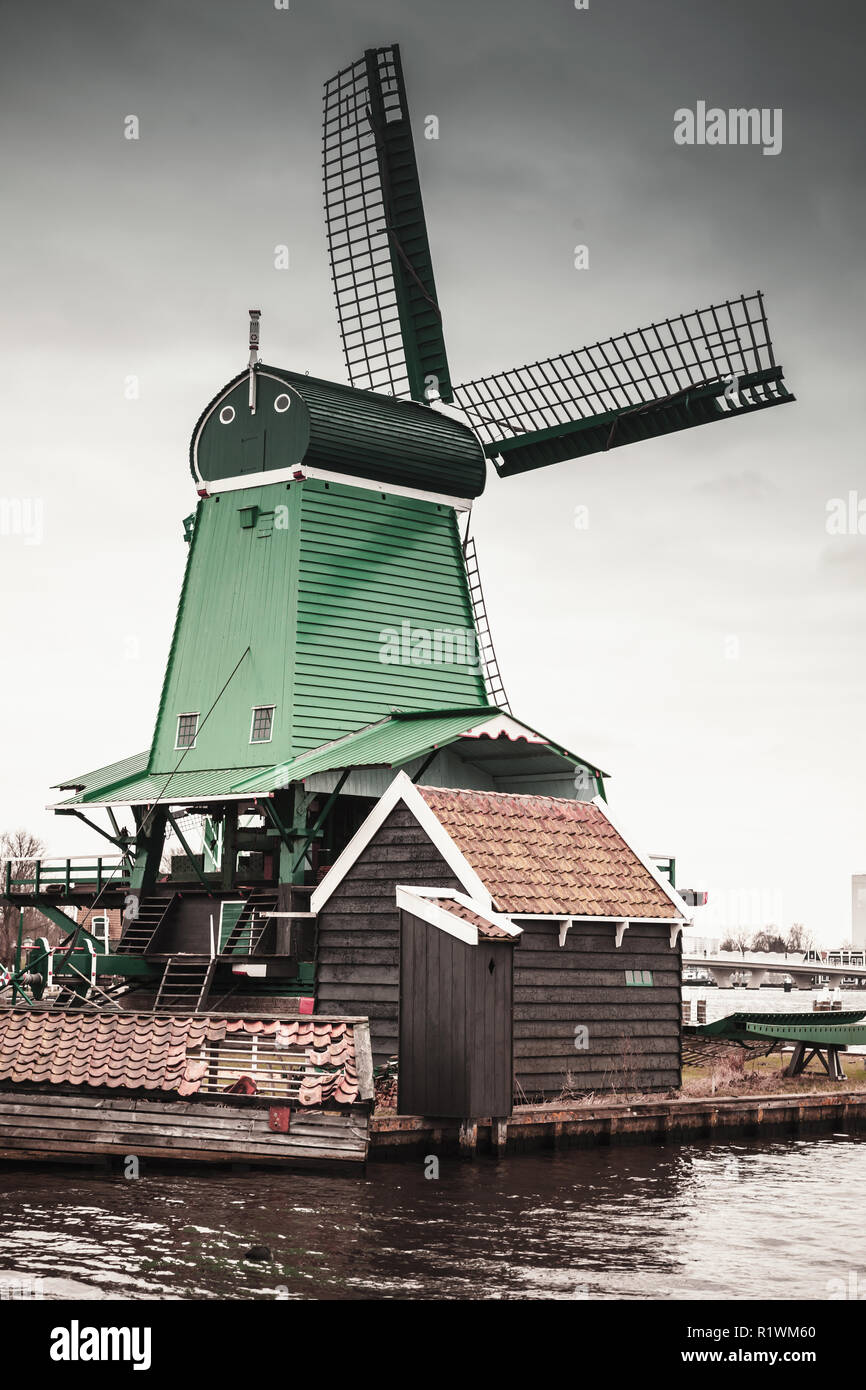 Windmühle bei bewölktem Himmel am Fluss Zaan Küste, Zaanse Schans Stadt, beliebten touristischen Attraktionen der Niederlande. Vorort von Amsterdam Stockfoto