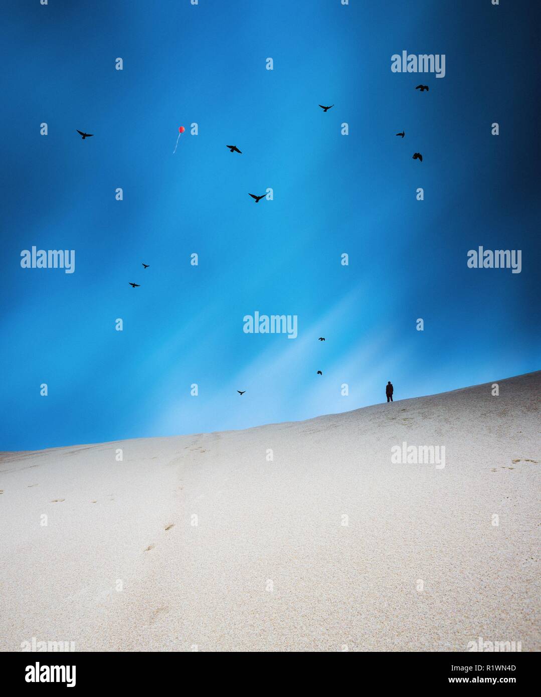 Surreale Landschaft mit Sanddünen unter man Silhouette und bei bewölktem Himmel am Abend. Stockfoto